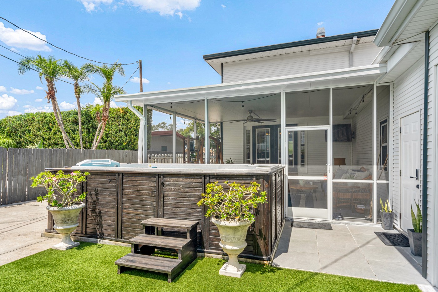 Backyard swim spa with wooden steps beside a screened porch and artificial turf, St. Petersburg home
