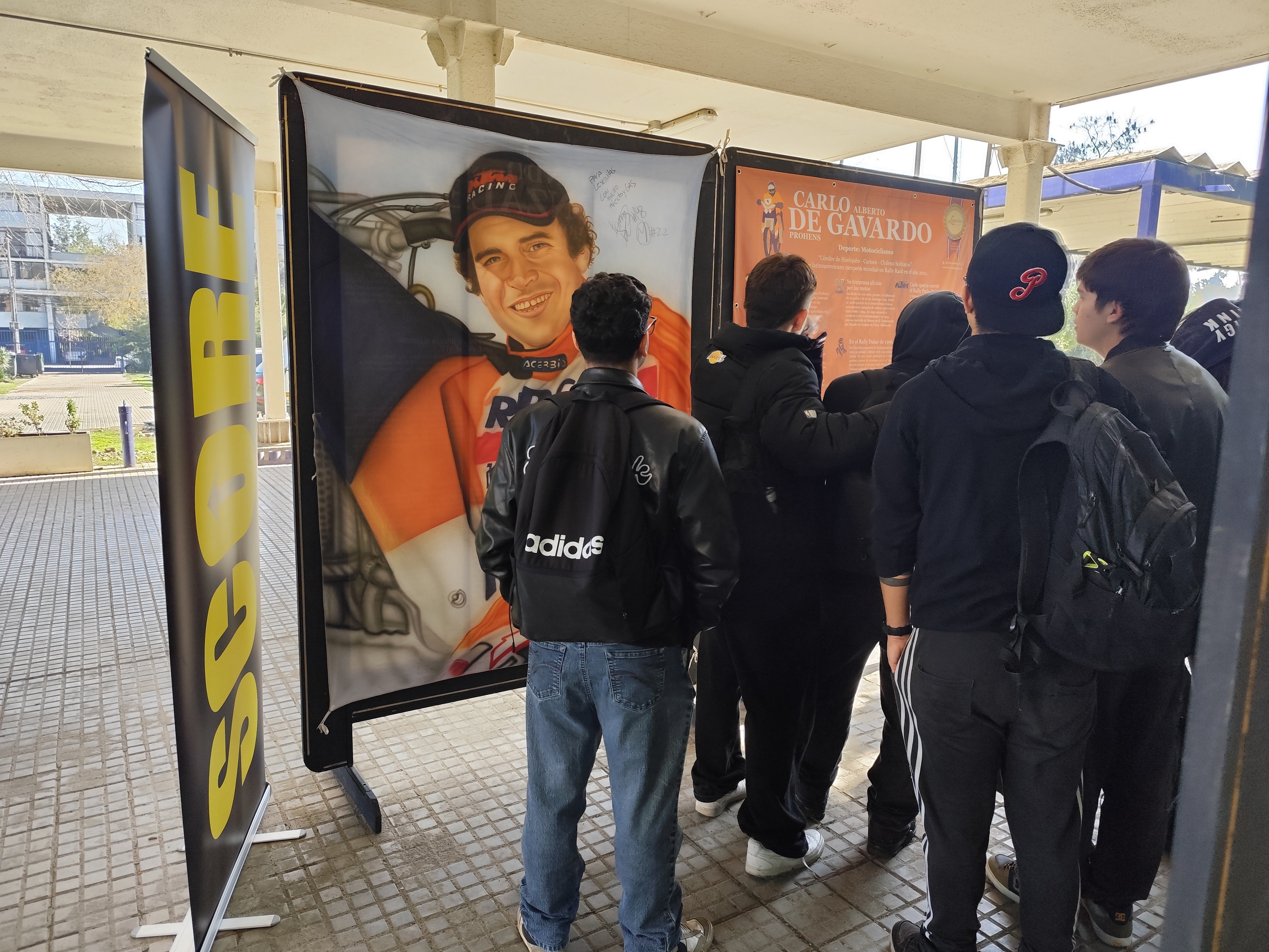 Asistentes observando la pintura de Carlo De Gavardo, motociclista chileno, en la exposición Leyendas del Deporte en USACH.