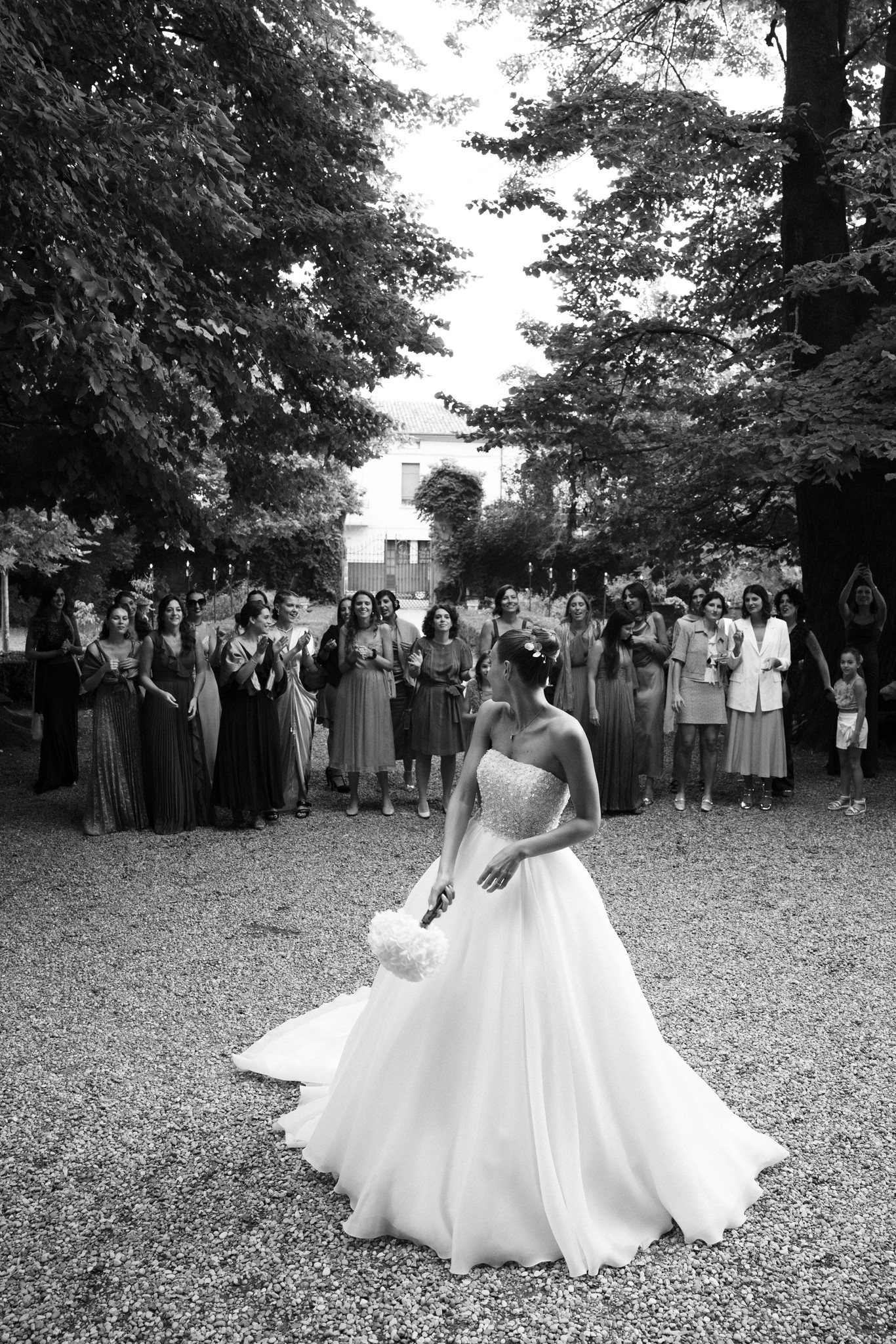 Sposa in abito bianco nel parco di Villa Ferrari, circondata dagli ospiti durante il ricevimento di matrimonio