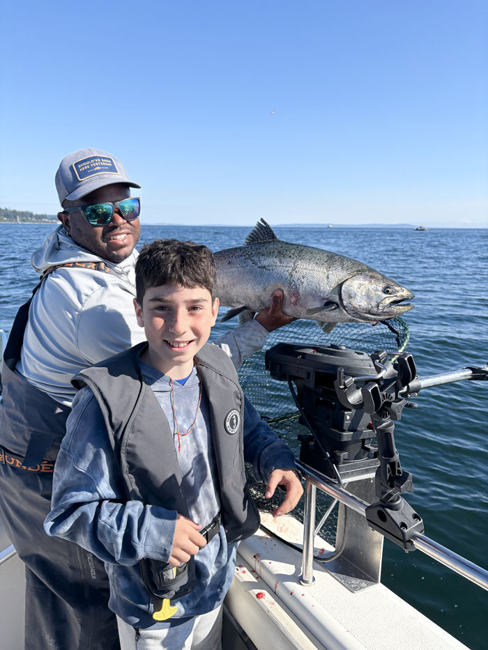 Captain Jerome and a kid with king salmon on Puget Sound fishing charter.
