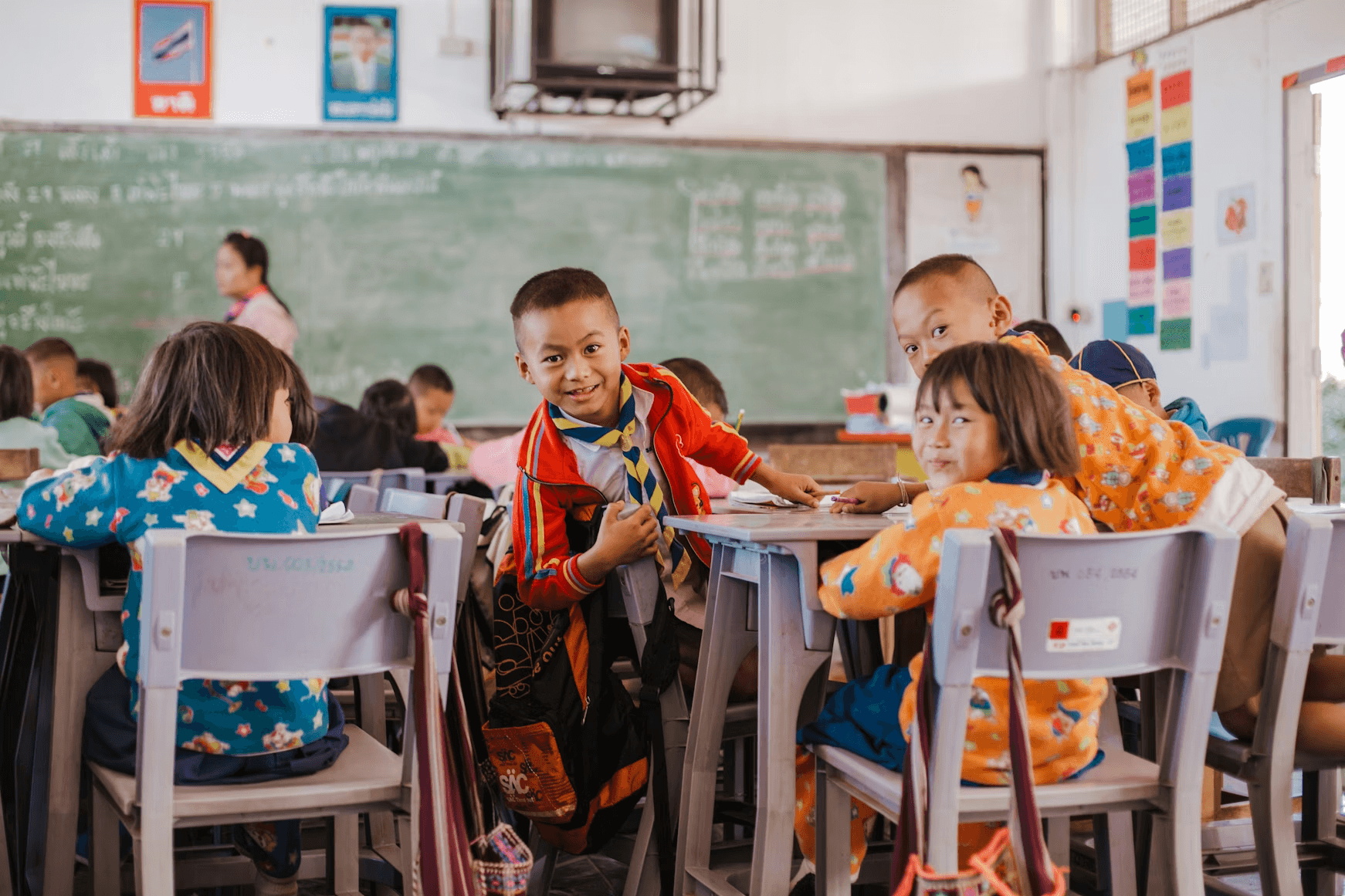 Children in a classroom, some wearing bright uniforms.