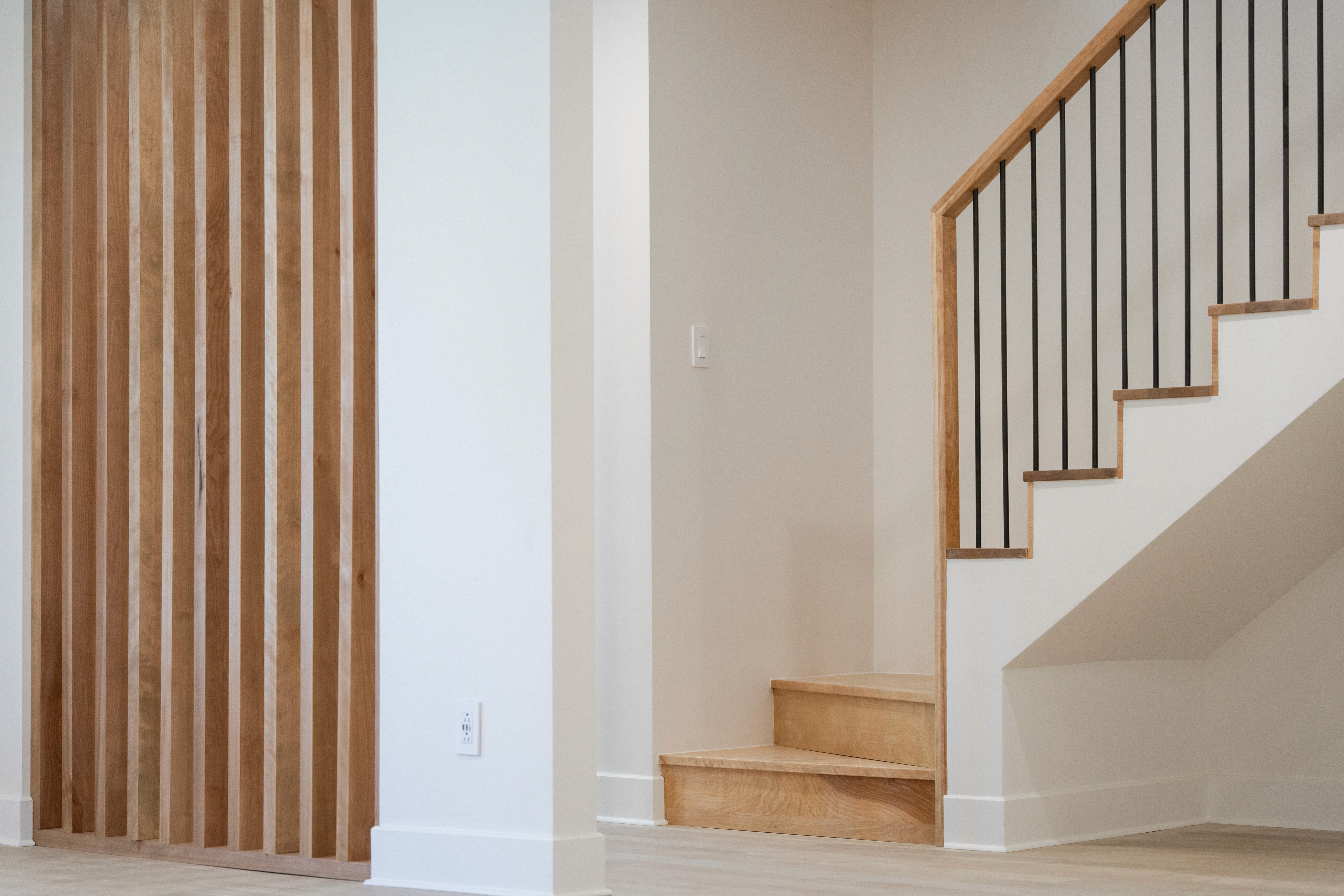 A softly lit hallway with a series of arched doorways, warm-toned walls, and wood flooring leading toward a seating area with neutral furniture.