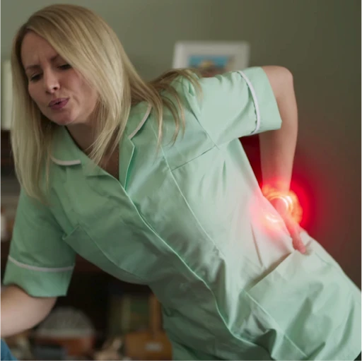 Female nurse in discomfort as she holds her lower back