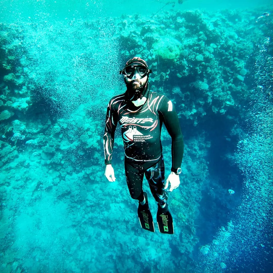freediver meister taking a selfie with a fish underwater