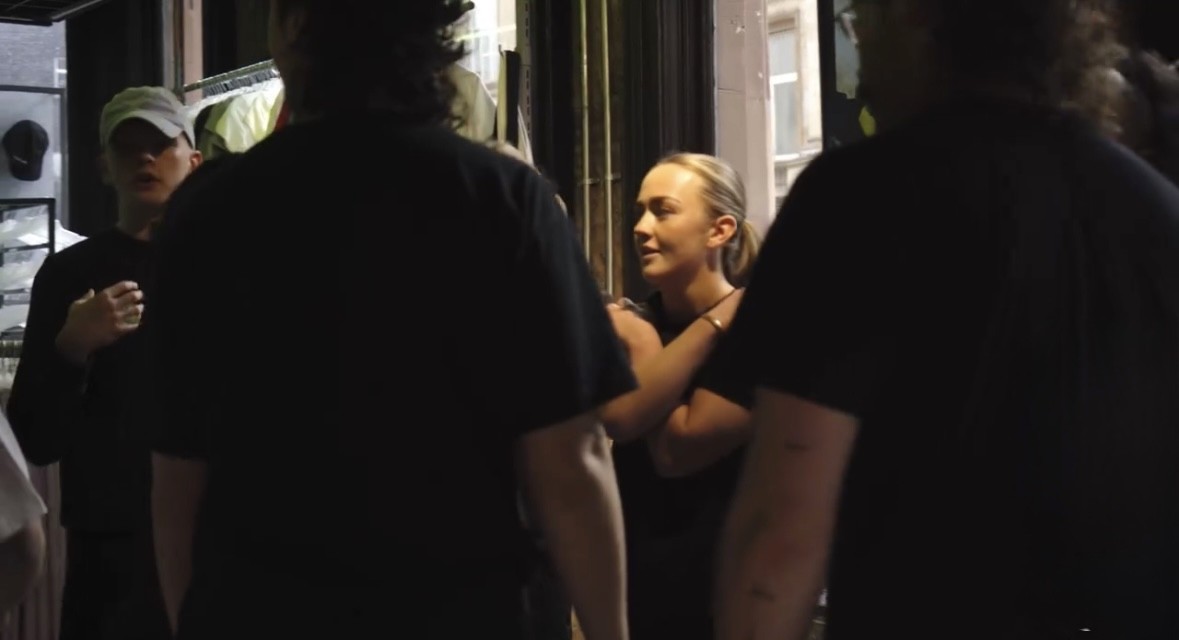 Group of young people talking outside a retail store during a street-style campaign shoot.