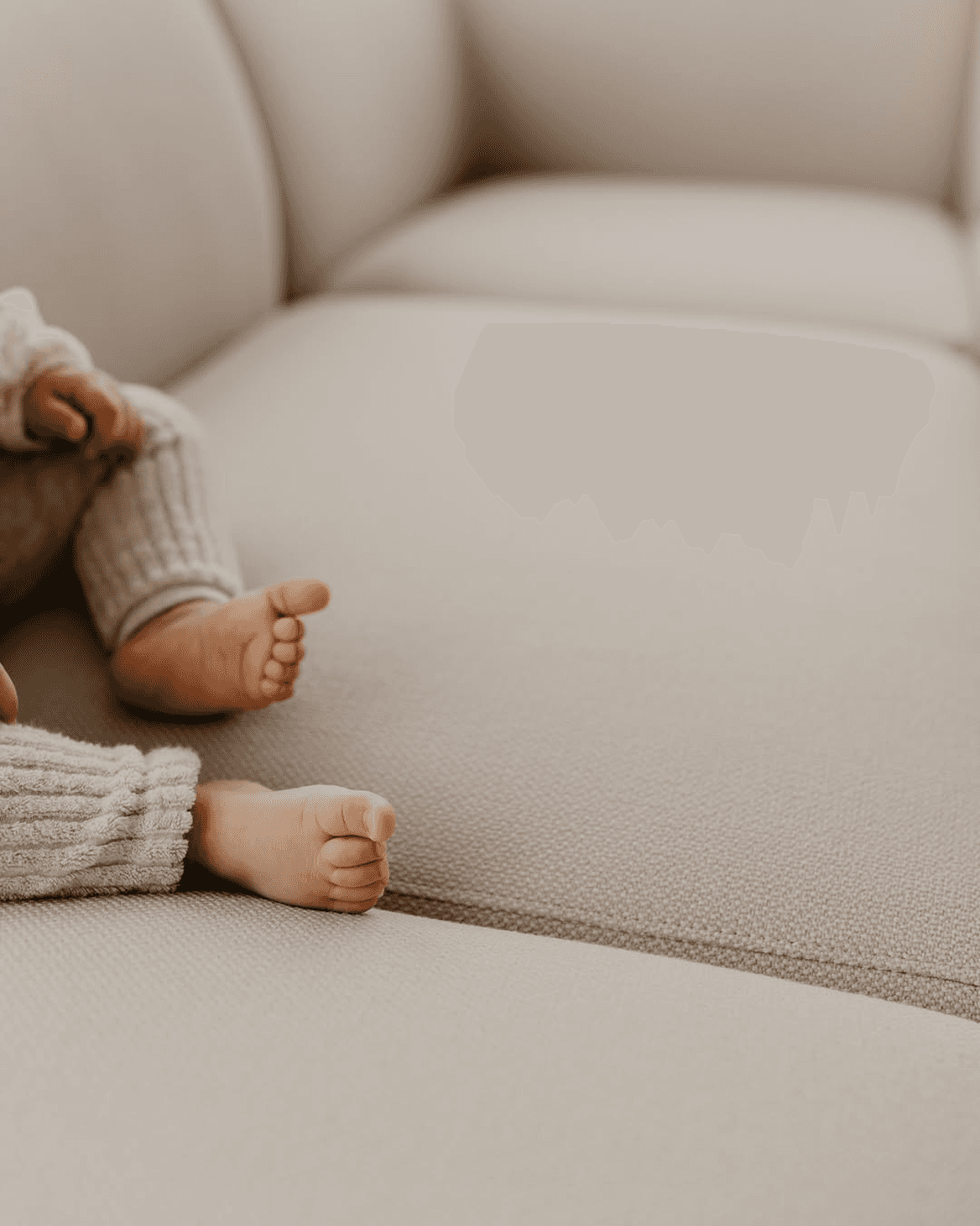 Baby's bare feet on a soft beige sofa