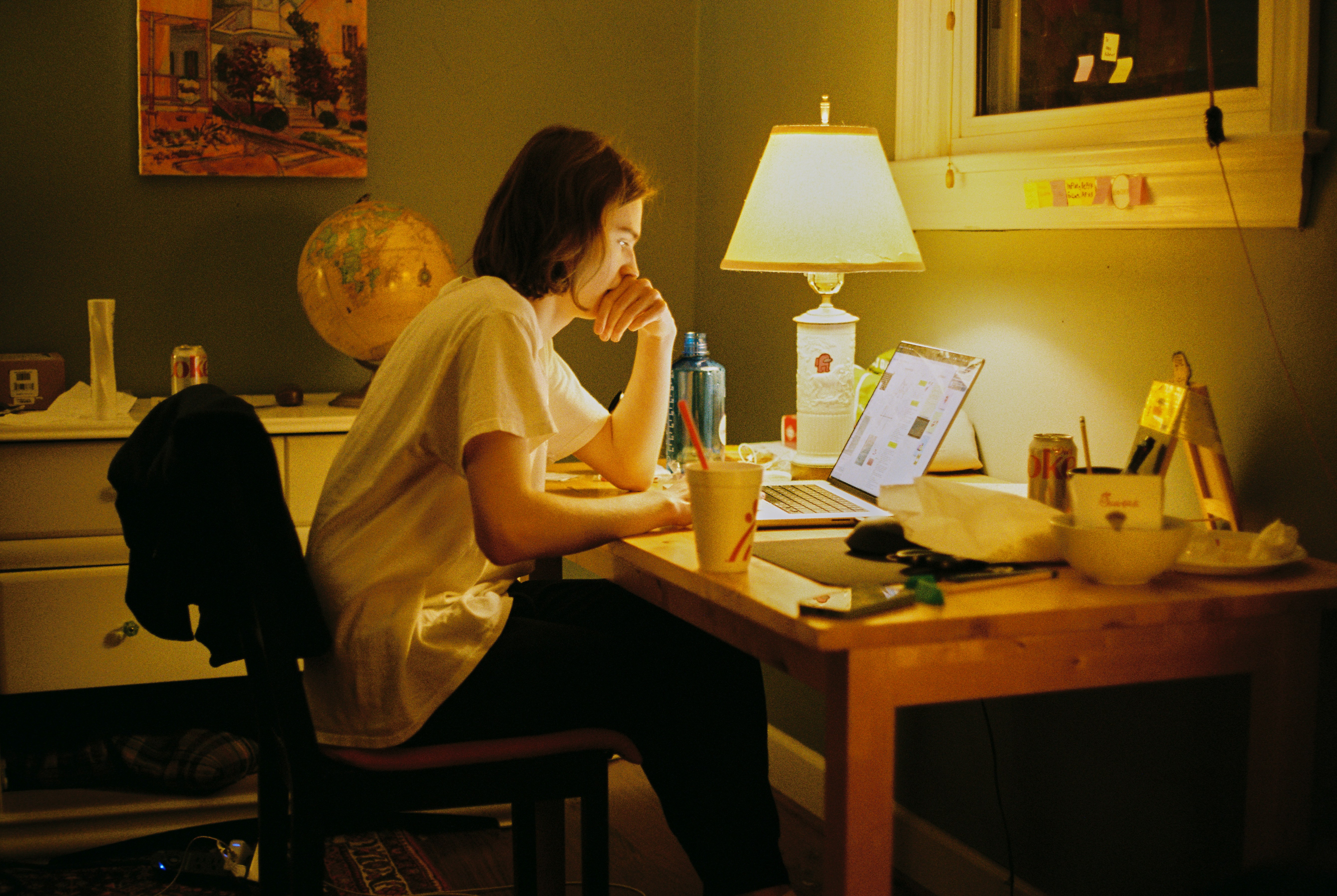 Person thoughtfully composing an email at a desk, warm light
