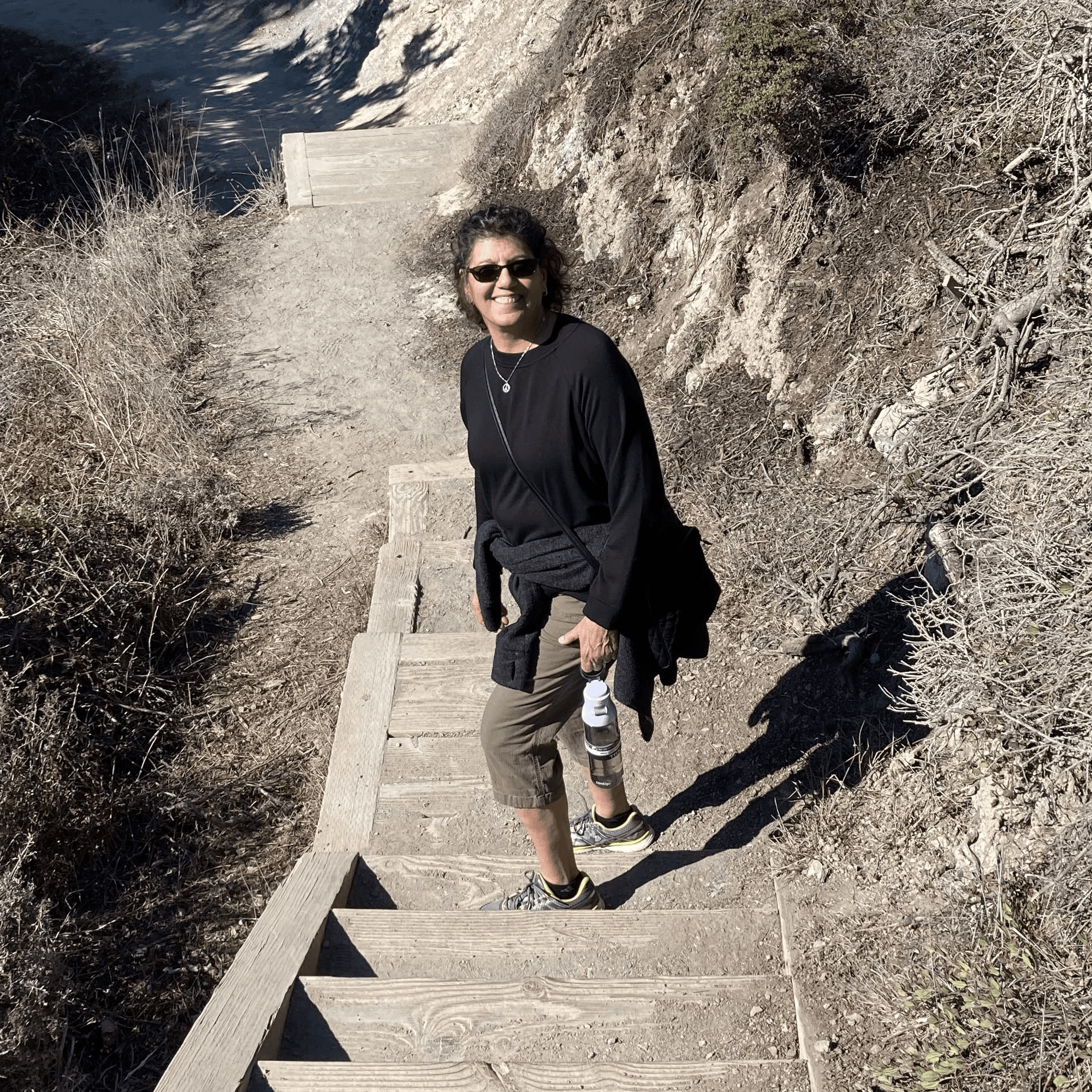 Carol Bruce, founder of Wellness Matters, smiling while hiking on a scenic trail, embracing wellness and balance.