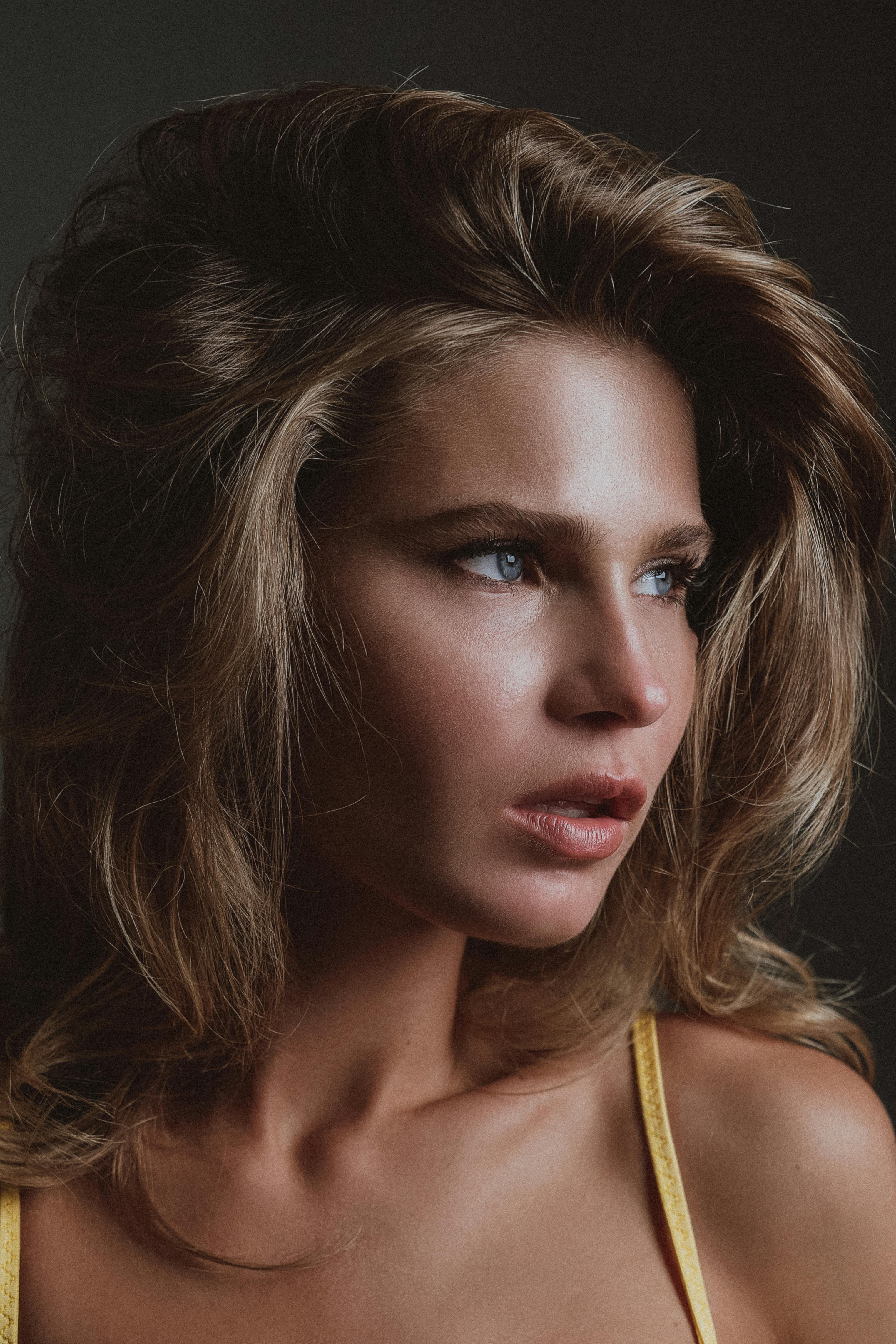Woman with blonde hair and blue eyes looking away.