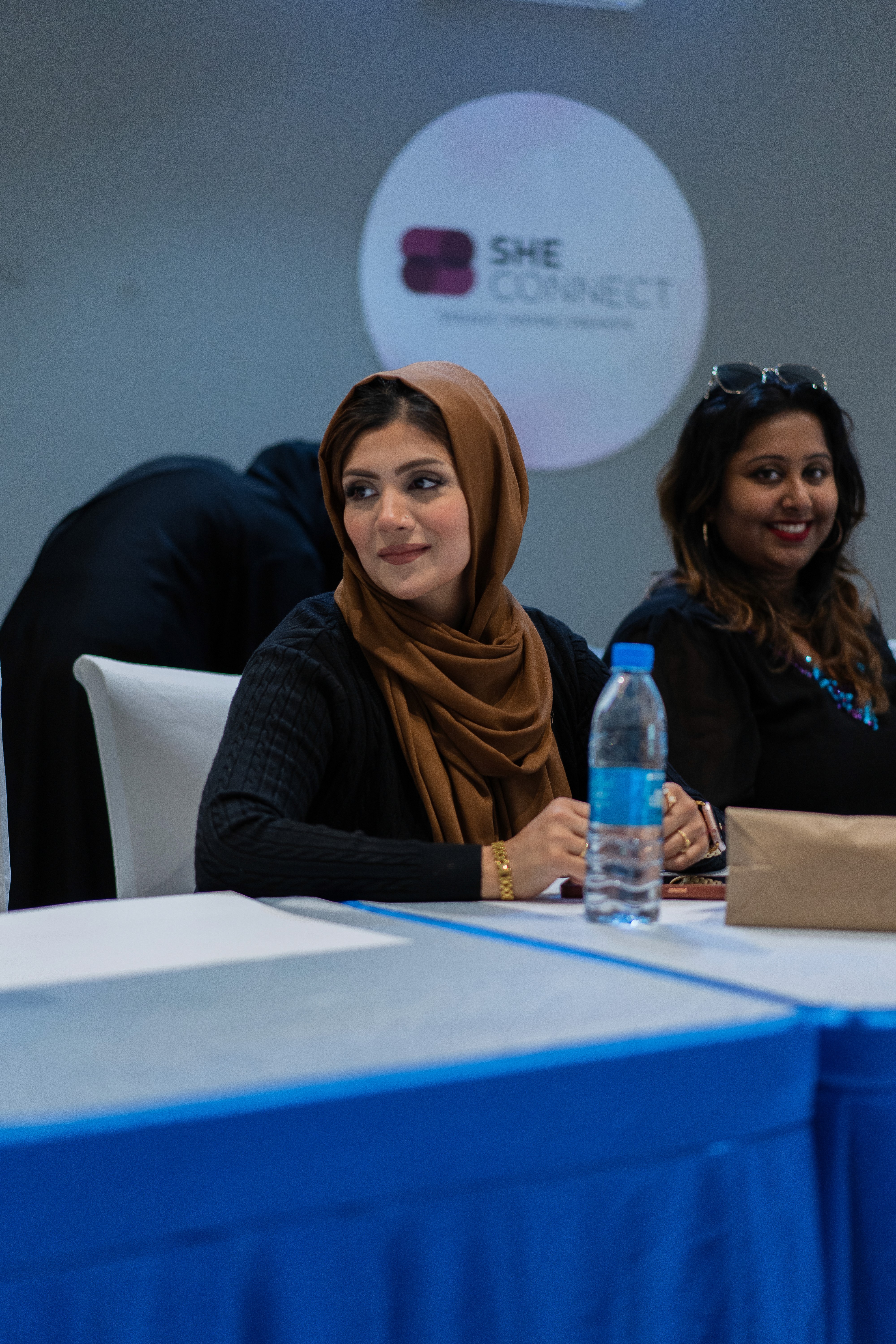 Smiling young man with short hair poses against a dark background, wearing a green button-up shirt.