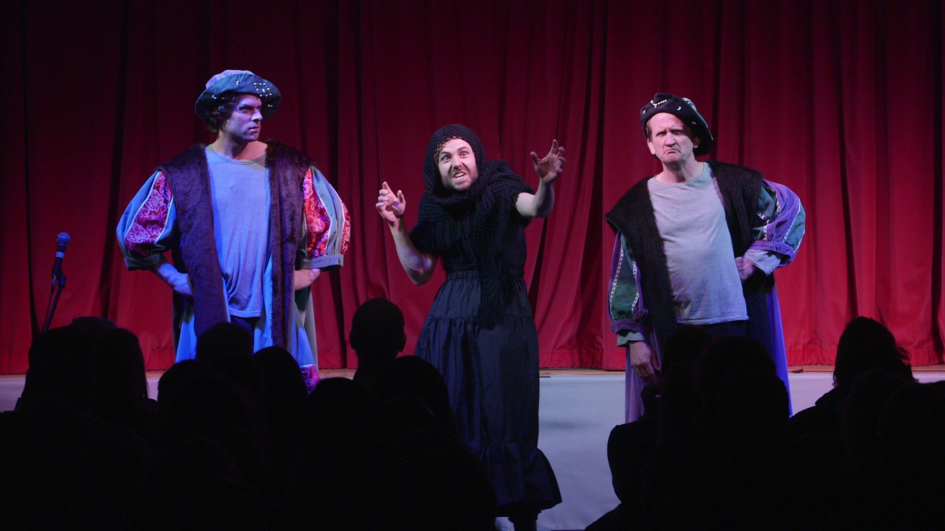 Three Frow Show performers in Tudor costume in front of a red curtain