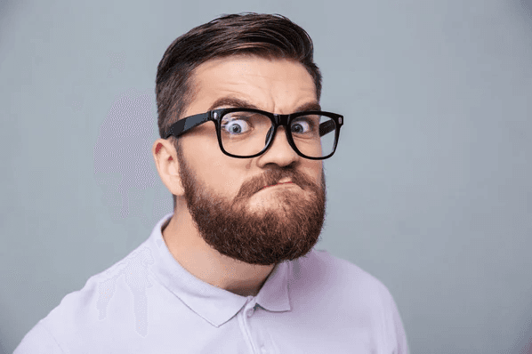 A person with glasses and a beard is looking at the camera.