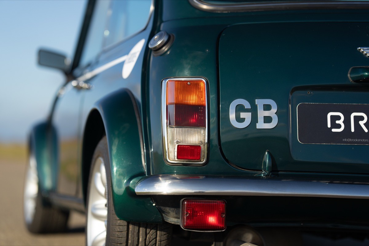 Close-up of the rear of a dark green vintage car with British flag details and 'GB' on the license plate.