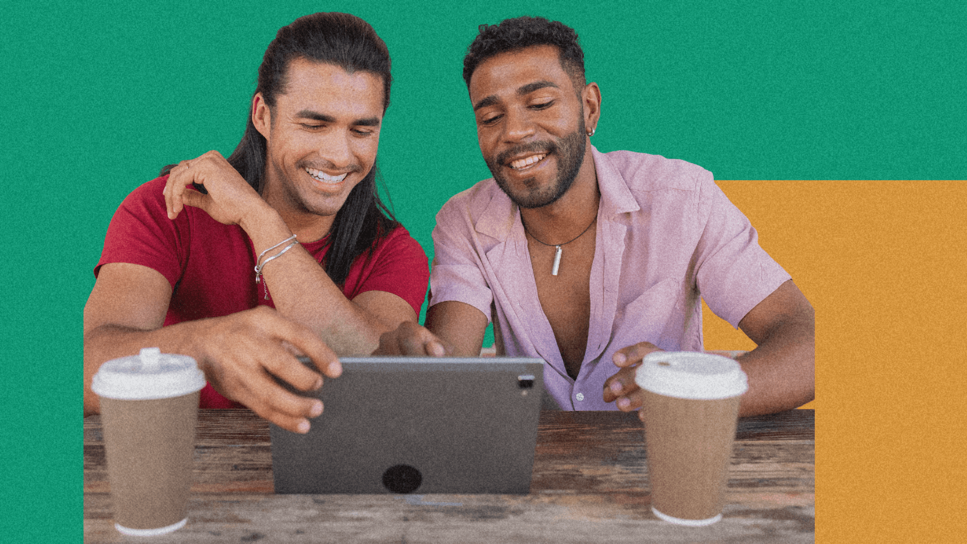 Two smiling men sit together at a table, looking at a tablet with coffee cups nearby, against a colorful background.