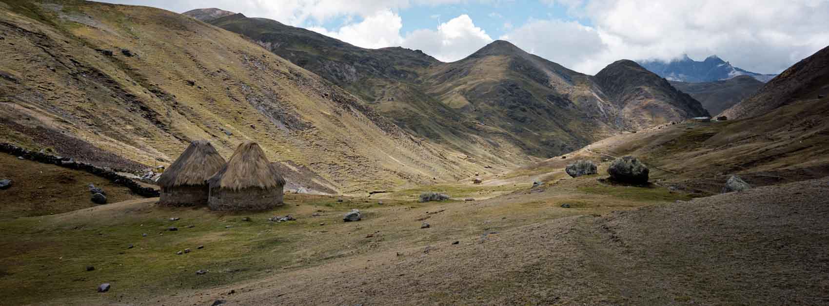 Panoramic film photograph taken near Machu Picchu elevation, showing local huts standing at high altitude in the Andean mountains, highlighting everyday life at high altitude.