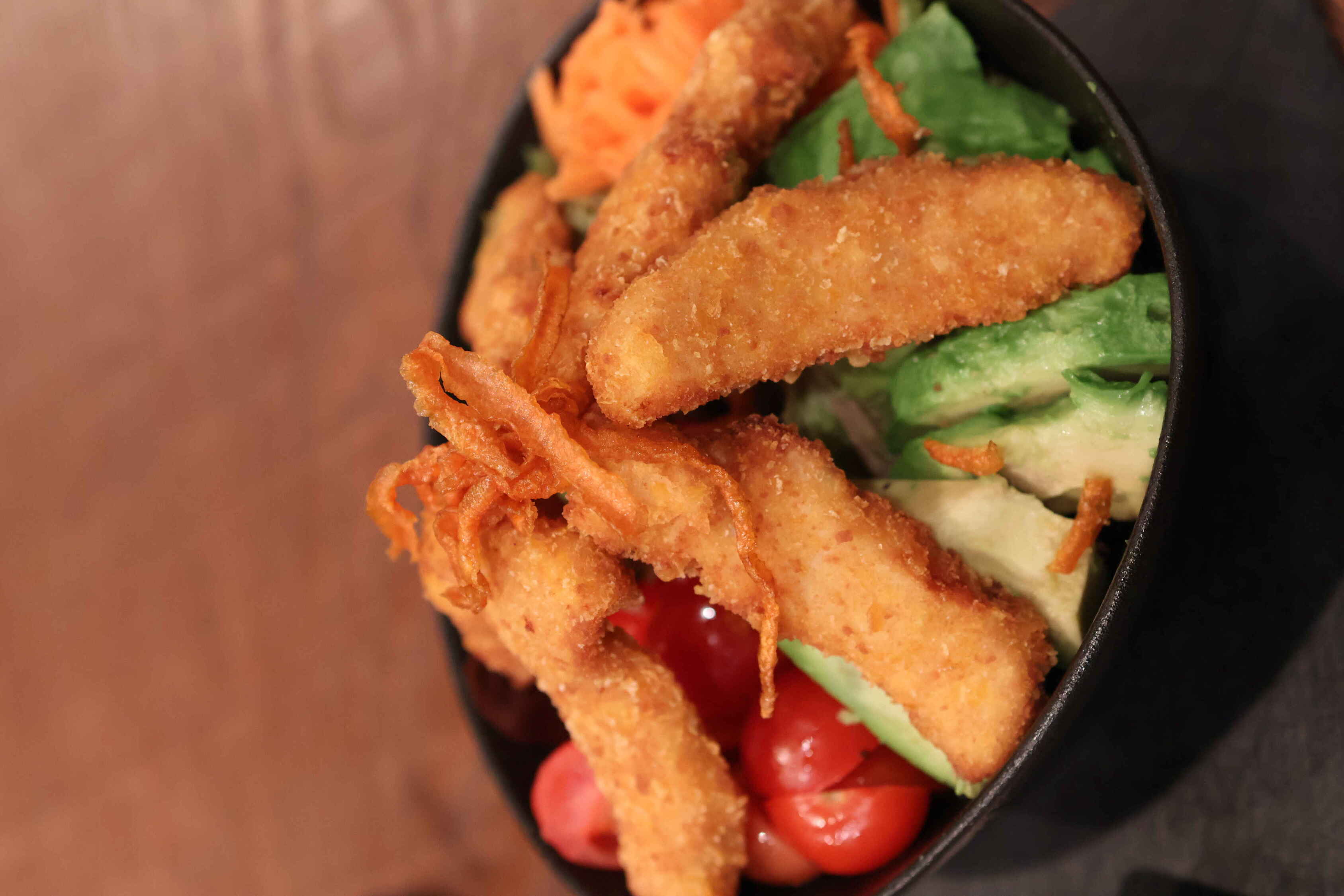 Overhead view of a kAlps Foodbar table spread with burgers, crispy fries, fondue dishes, a red cocktail, dipping sauces, and fresh garnishes arranged on slate serving boards.