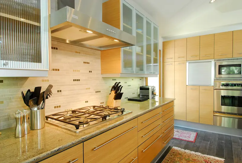 Bright kitchen with light wood cabinets, gas stove, frosted glass, and two ovens. Irvine Transitional Modern. Photo by Chris Darnall.