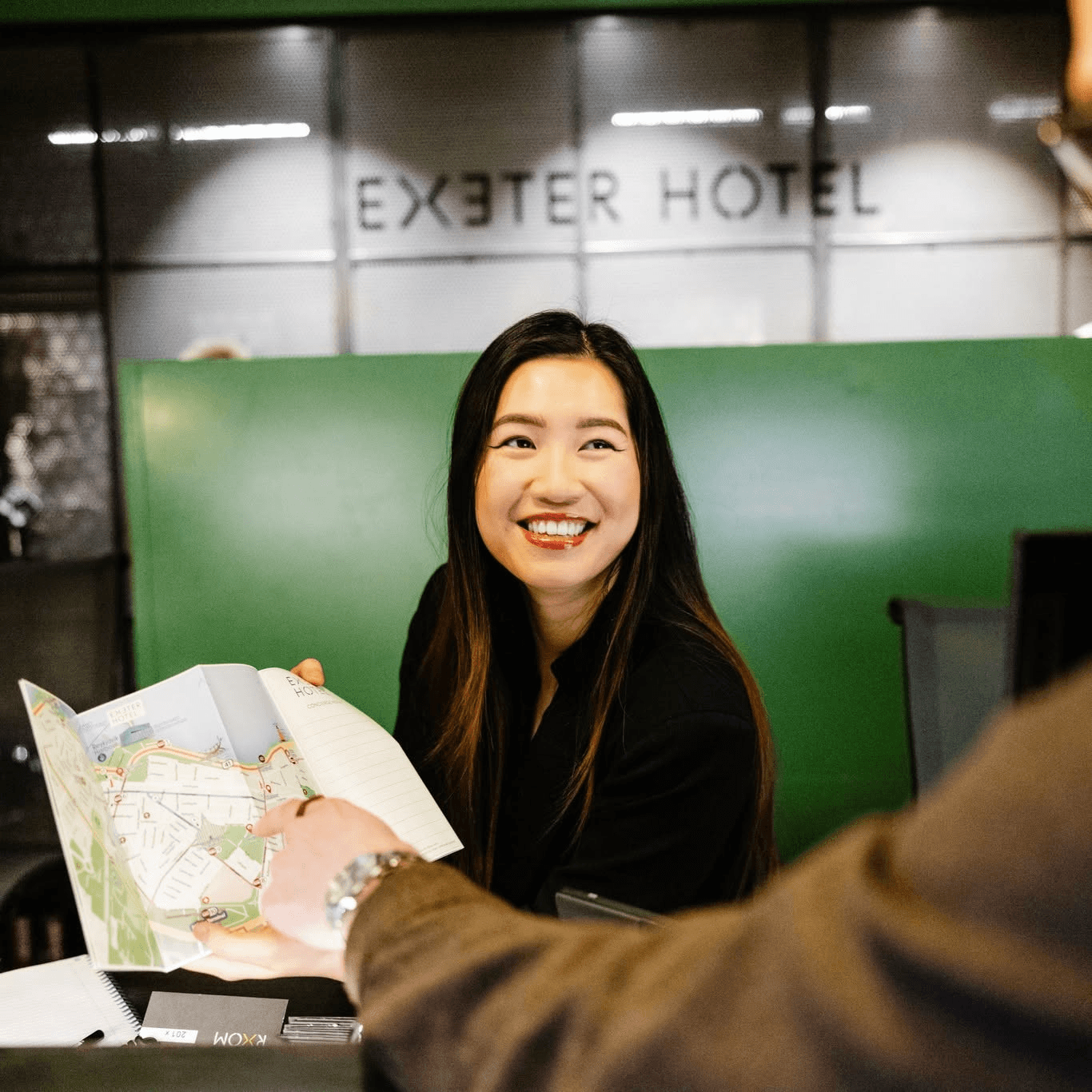 Exeter Hotel staff member smiling while showing a city map to a guest.