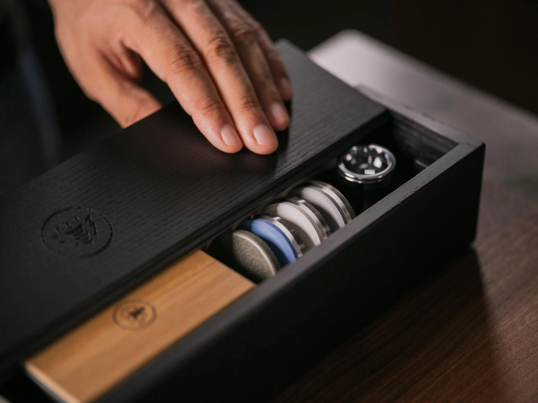 Hand öffnet die schwarze HORL®3 Box, in der der HORL3 Eiche Rollschleifer, vier zusätzliche Schleifscheiben und die HORL® Lupe, alle ordentlich untergebracht sind.