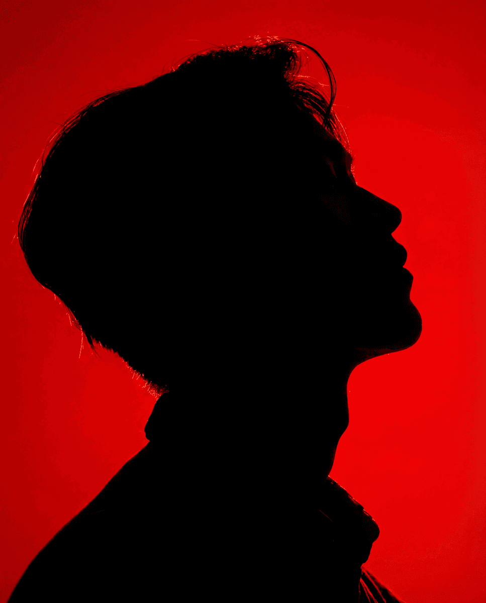 A person wearing sunglasses in red lighting