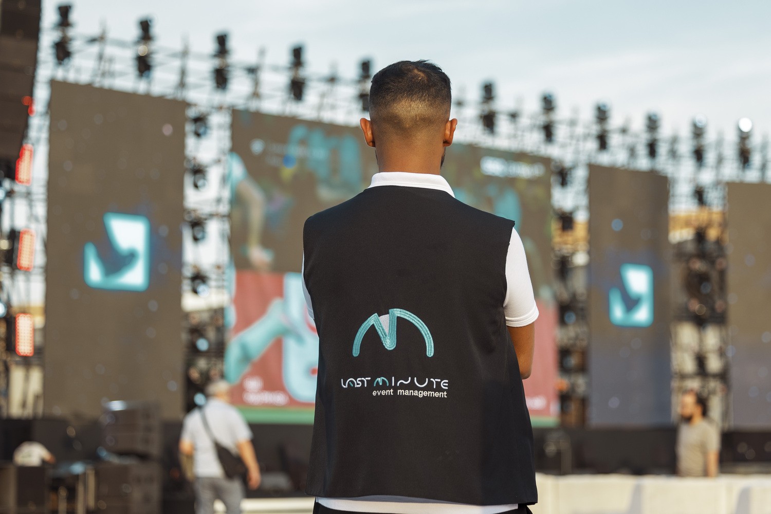 أحد أعضاء فريق لاست منت يقف أمام مسرح إنتاج خارجي كبير