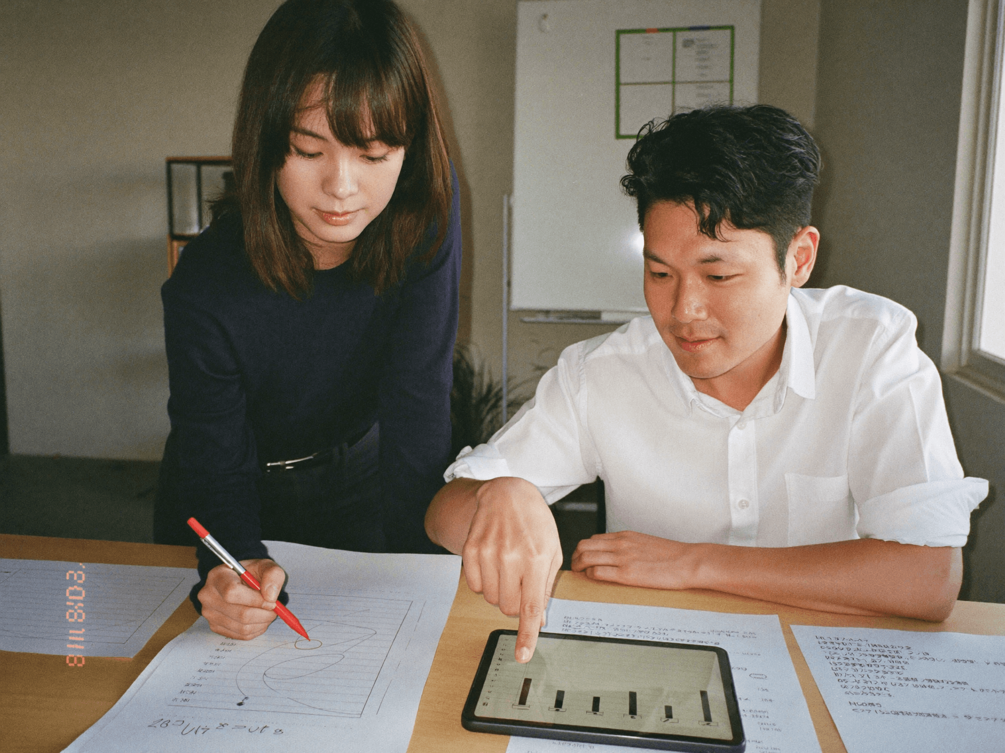 画面を指差しながらペアで実装を進める20代のエンジニア