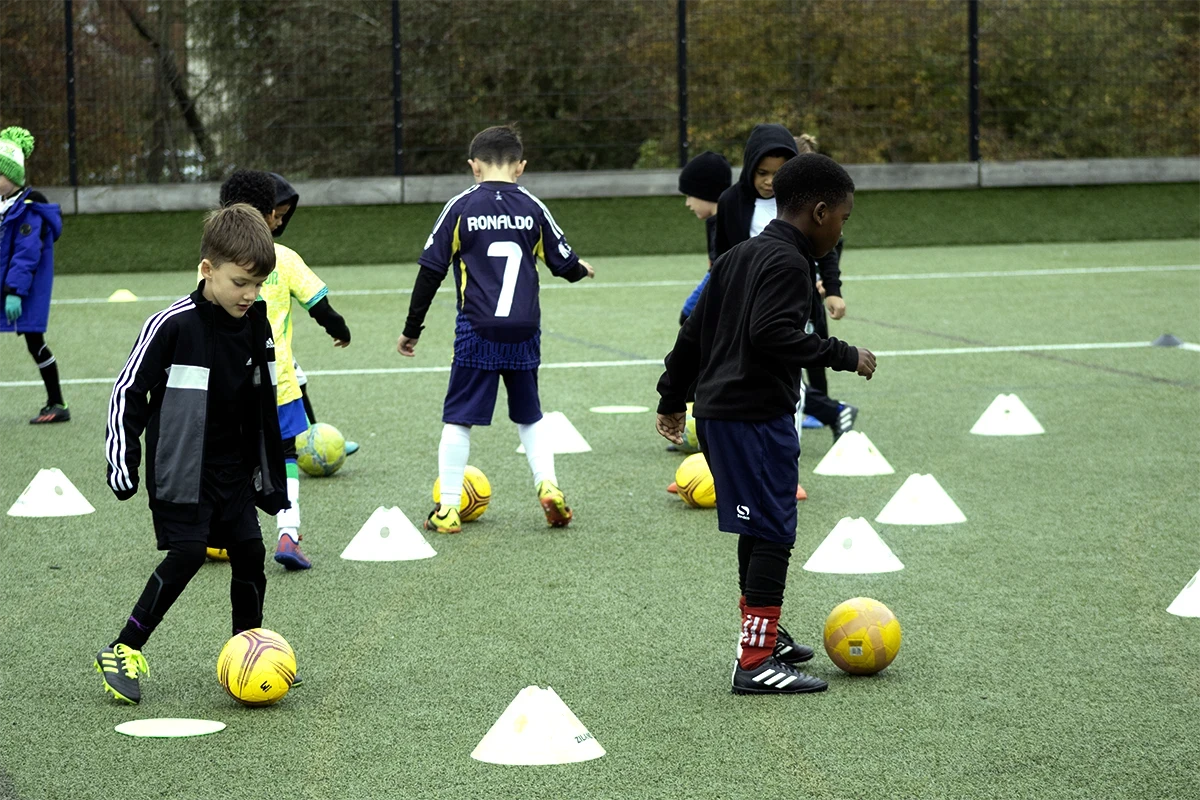 Kids dribbling between cones