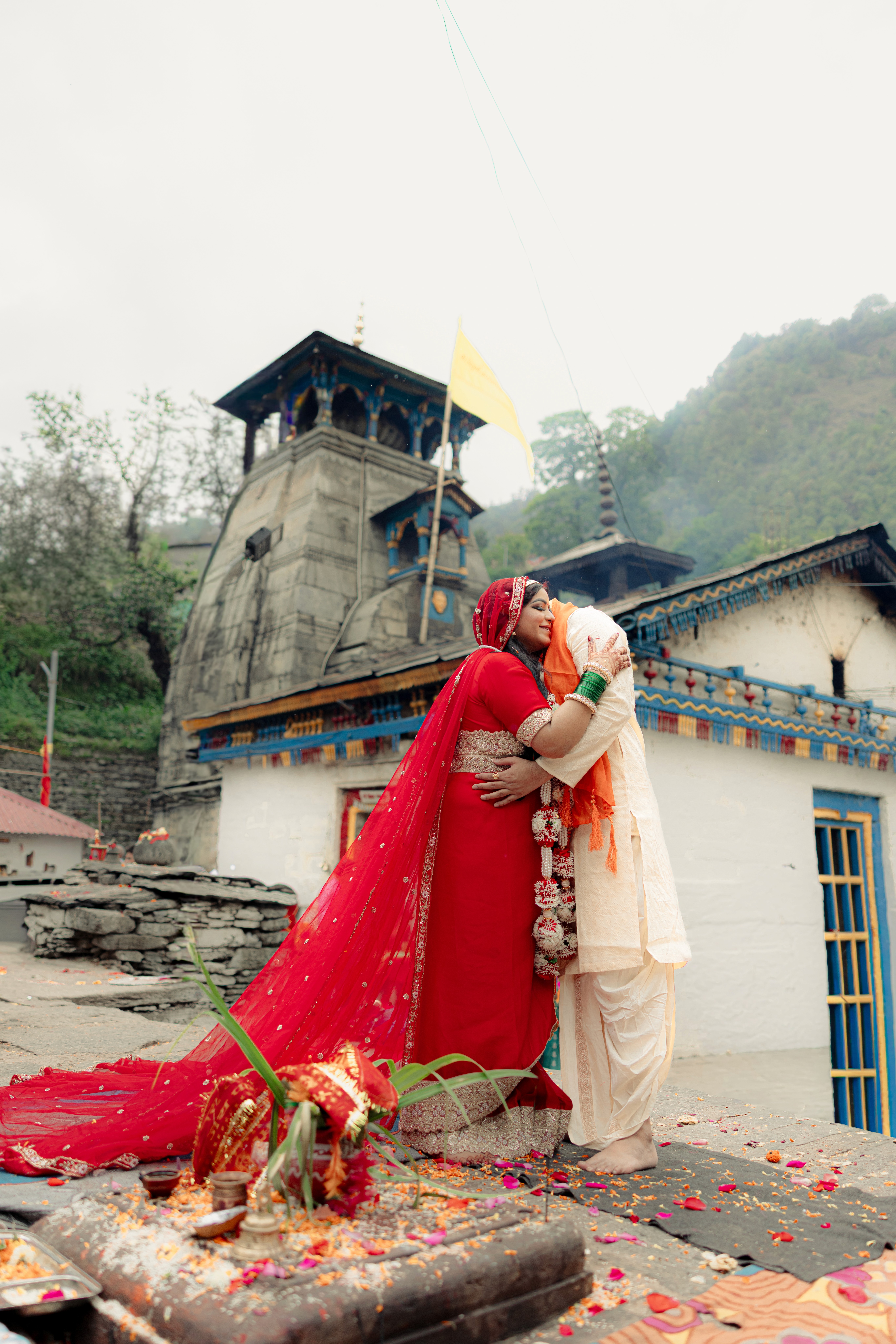 Bride and groom embracing outside a temple during an Indian wedding