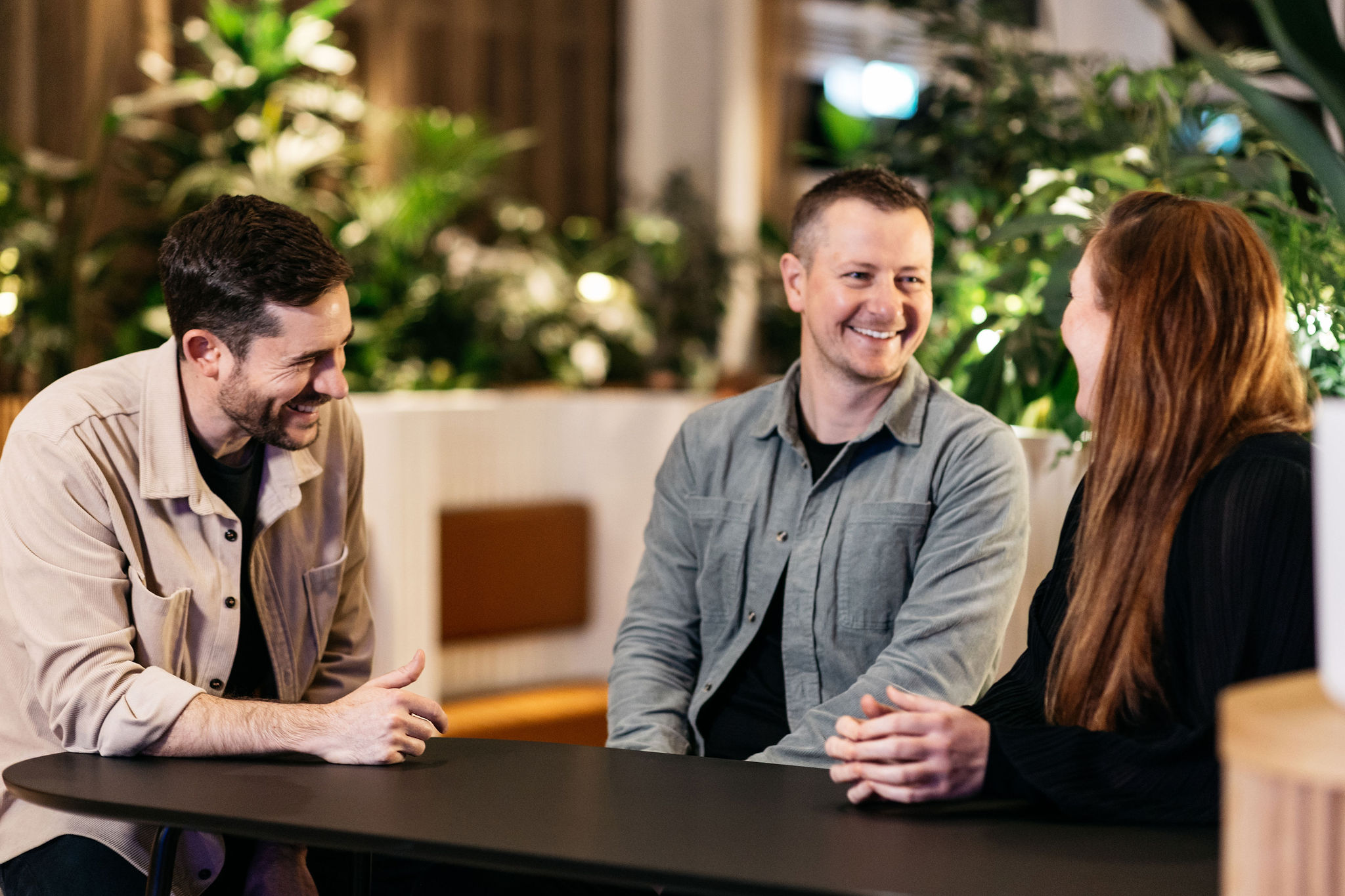 Three people talking and laughing around a table