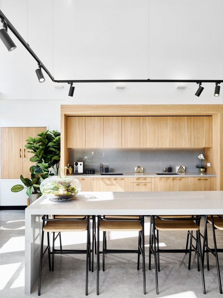 woman in blue dress shirt and blue denim jeans standing beside brown wooden chair