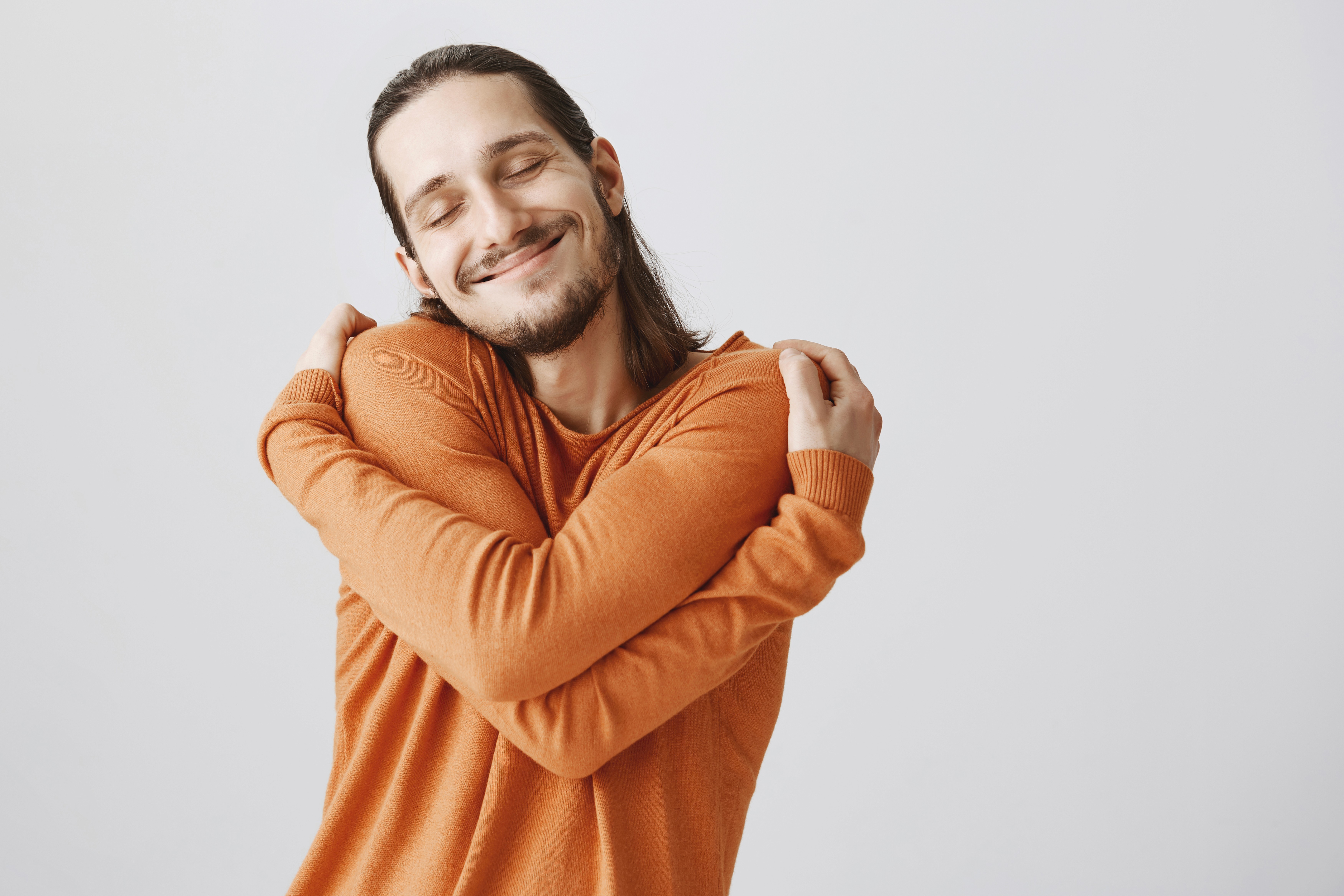 Homem se abraçando em sinal de autocuidado