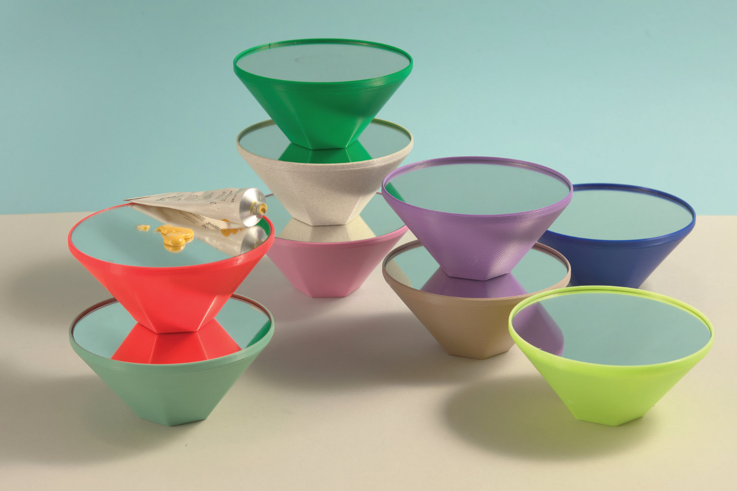 Colorful small mirrors in various shapes and sizes arranged playfully against a light backdrop.