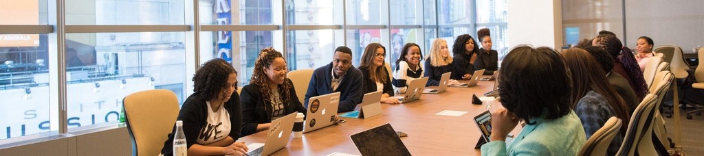 Diverse business team collaborating in modern conference room with laptops.