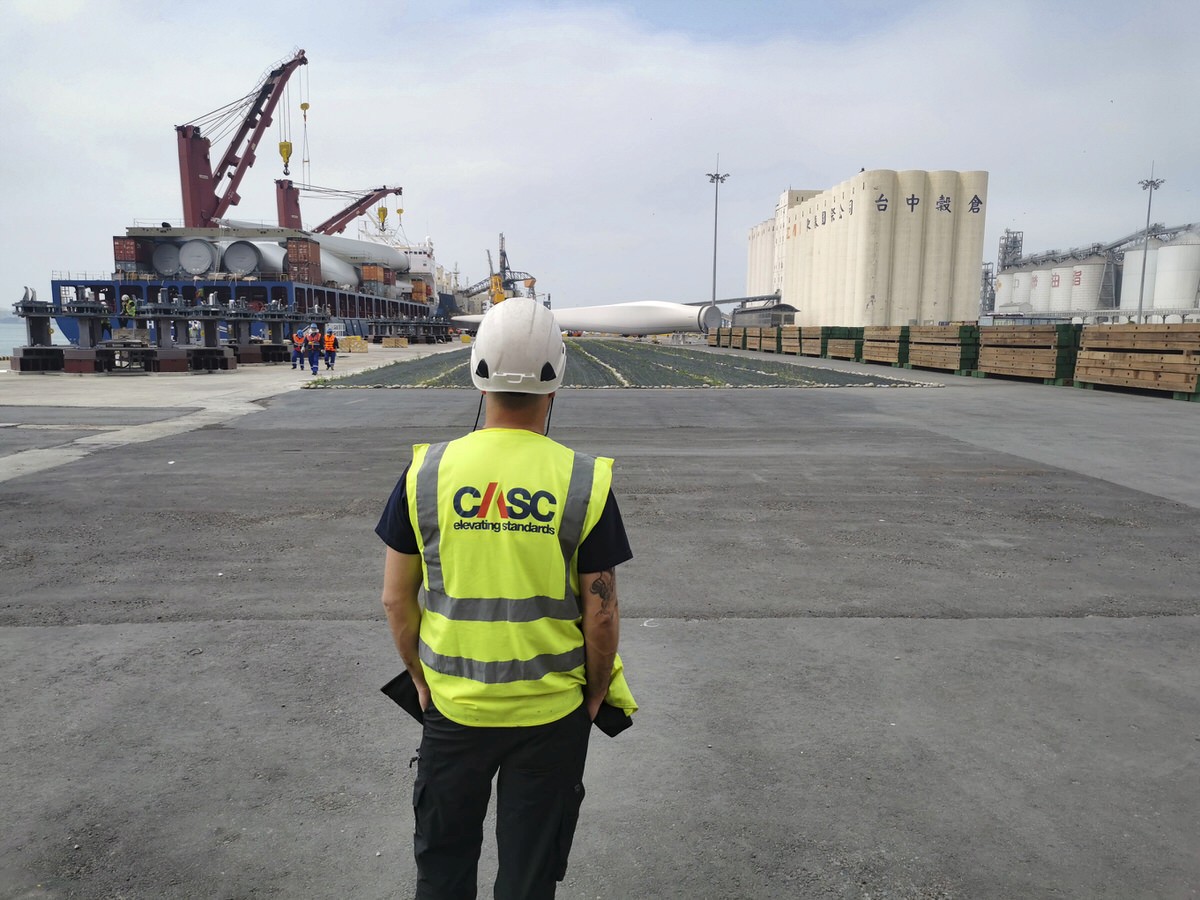 Site technician wearing high-visibility PPE walking through an offshore wind port facility.