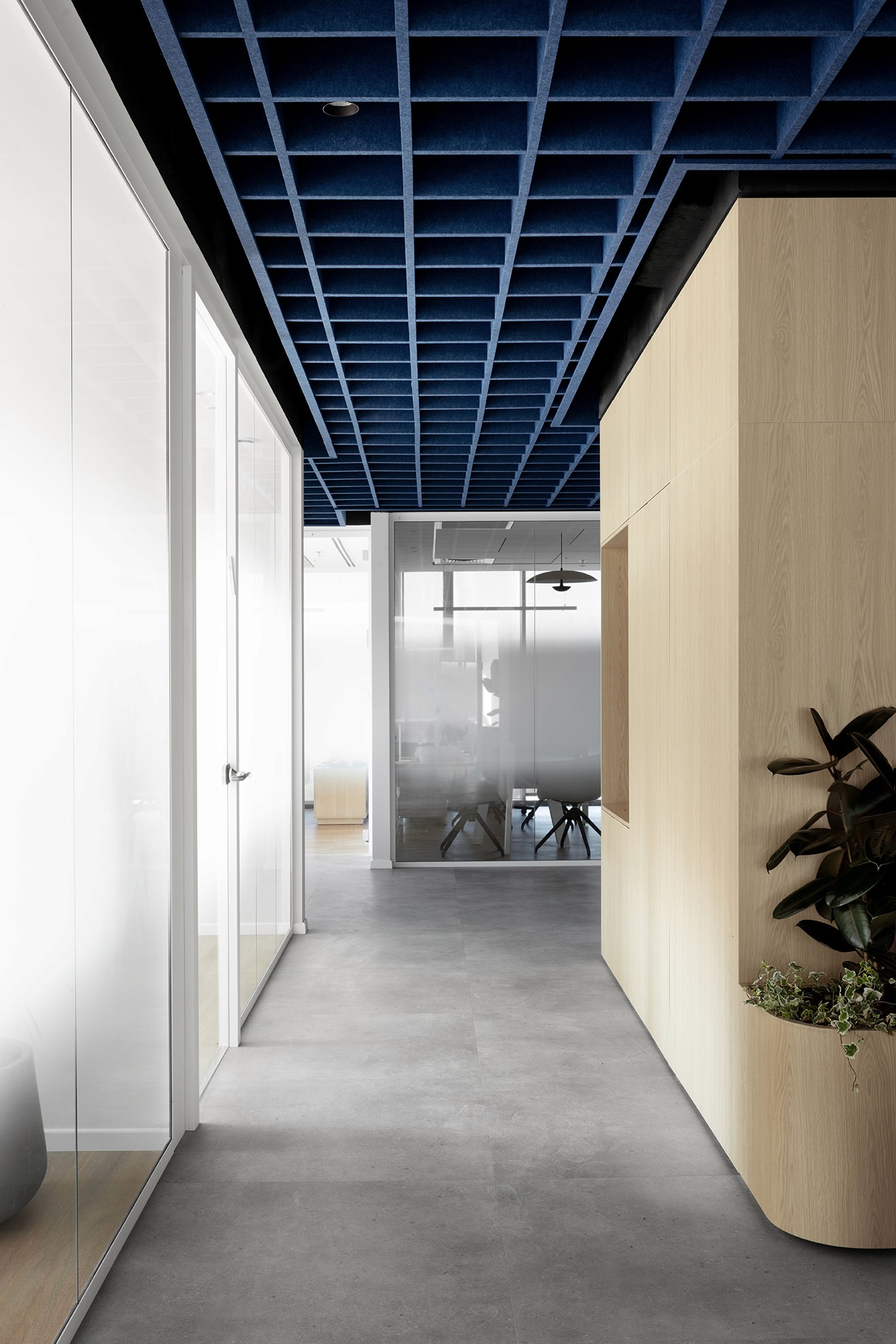 שקיפות במשרד: מבט דרך דלתות הזכוכית אל חדר הישיבות המעוצב, המציג הצצה לאומנות הקיר הכחולה ולריהוט היוקרתי.