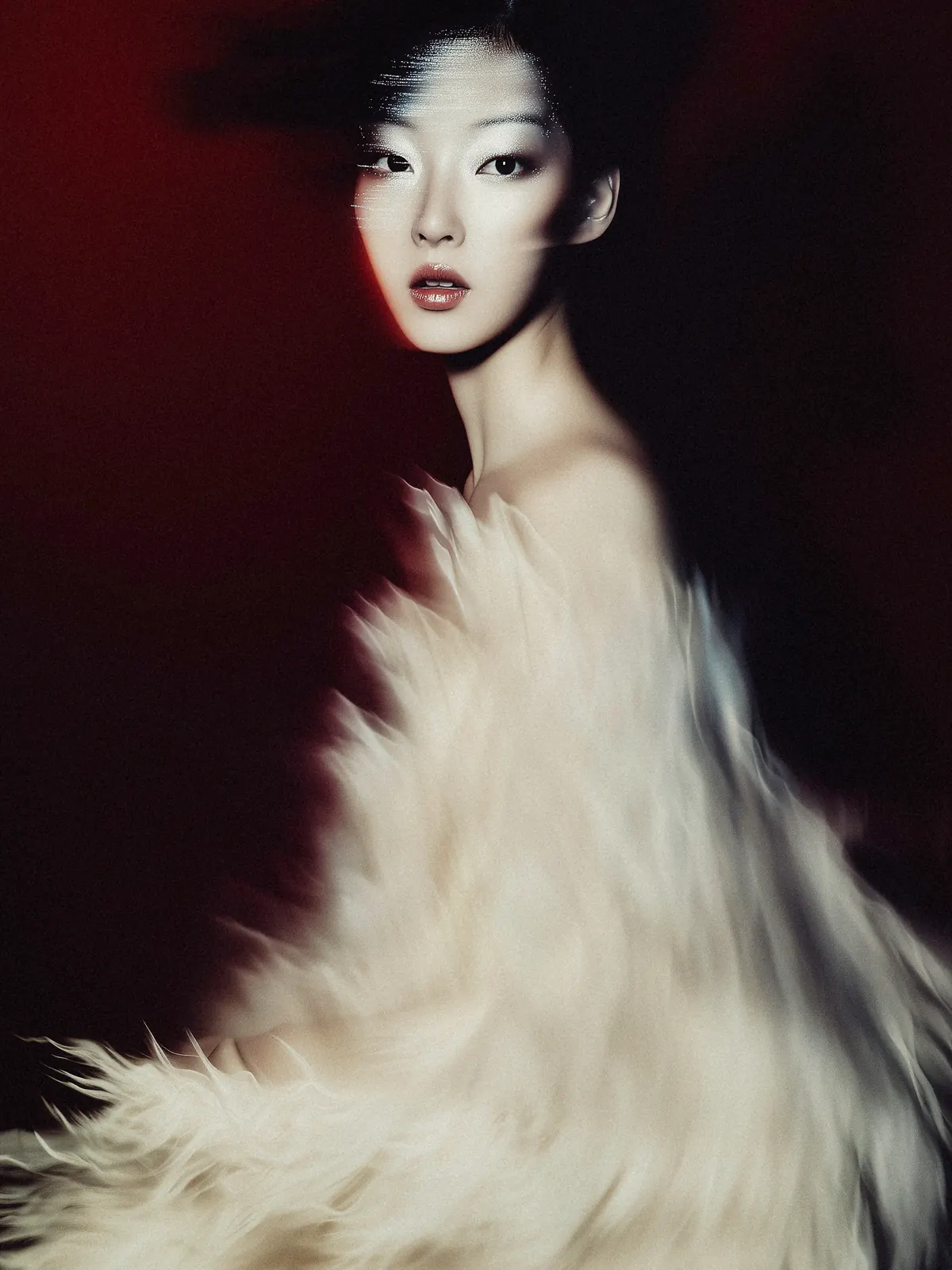 Fashion portrait in a white feathered garment against a dark red background.