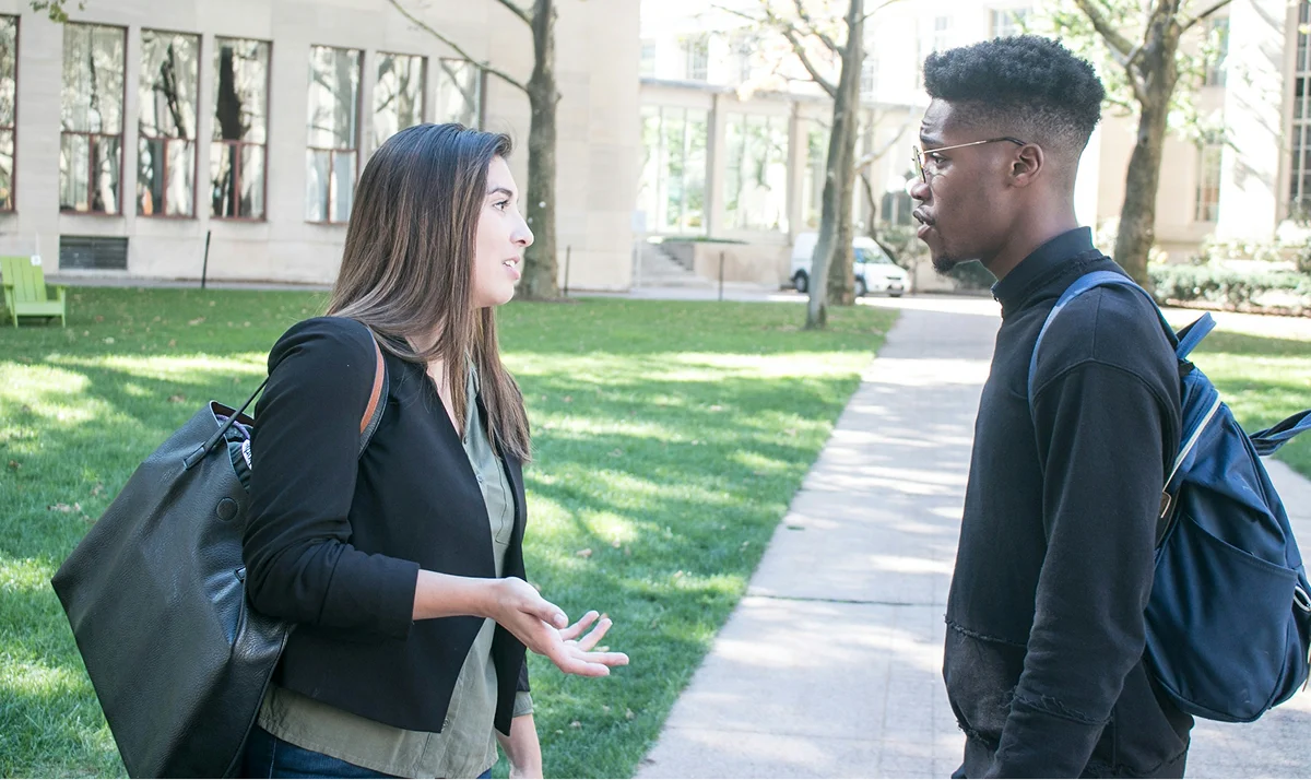 Two students talking outside a university building.
