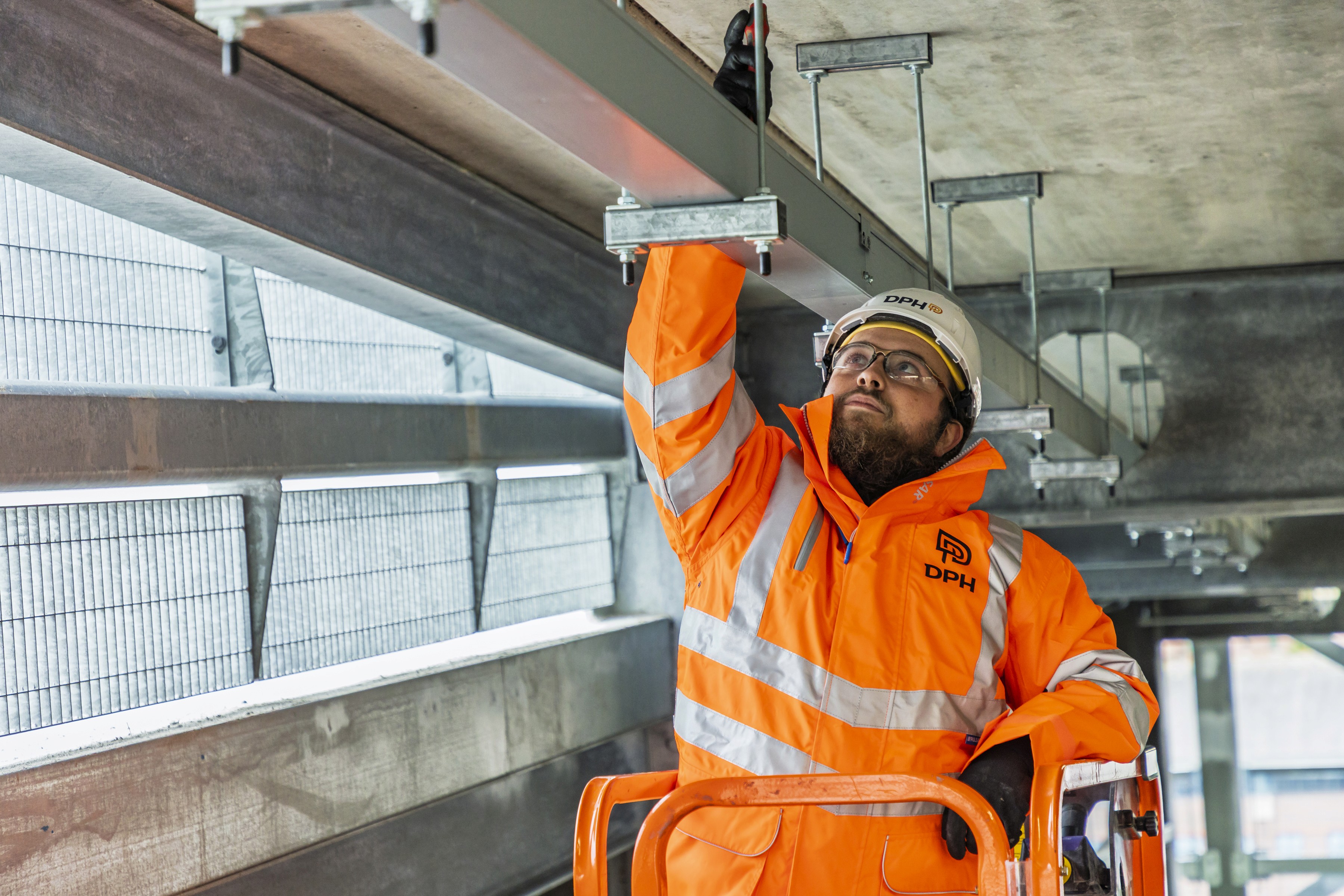 Modern glass building with illuminated facade and trees at sunset