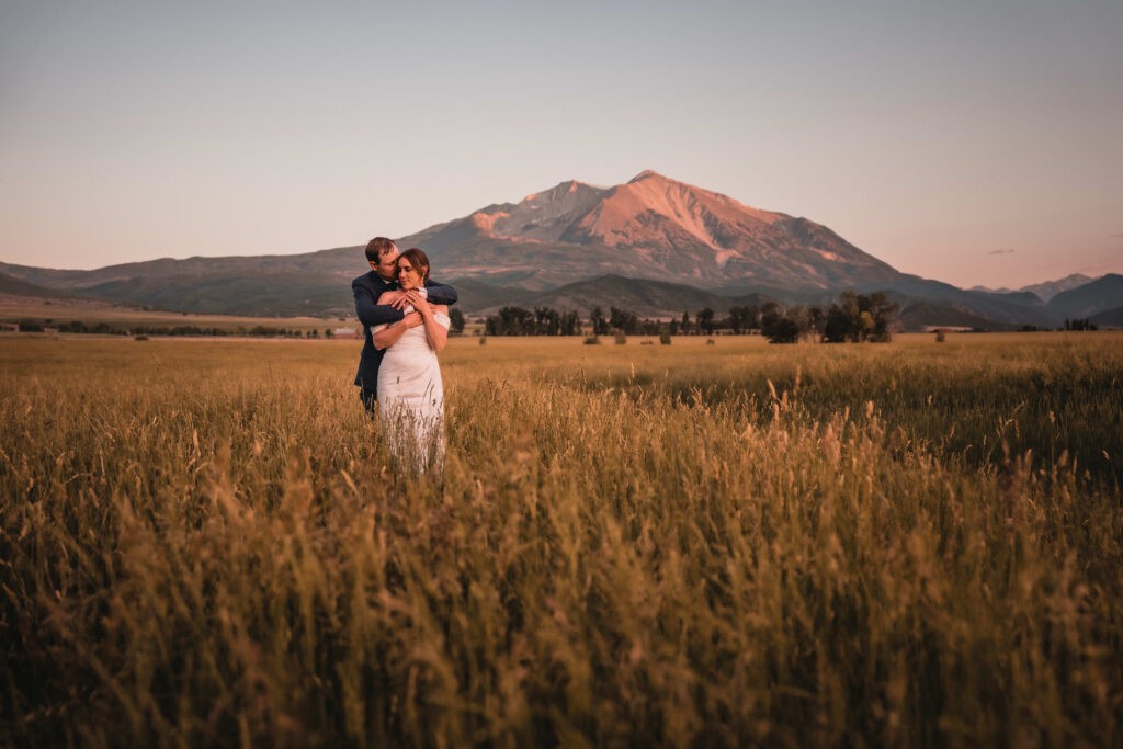 Bride and groom in field with Mount Sopris at Carbondale Private Ranch Wedding