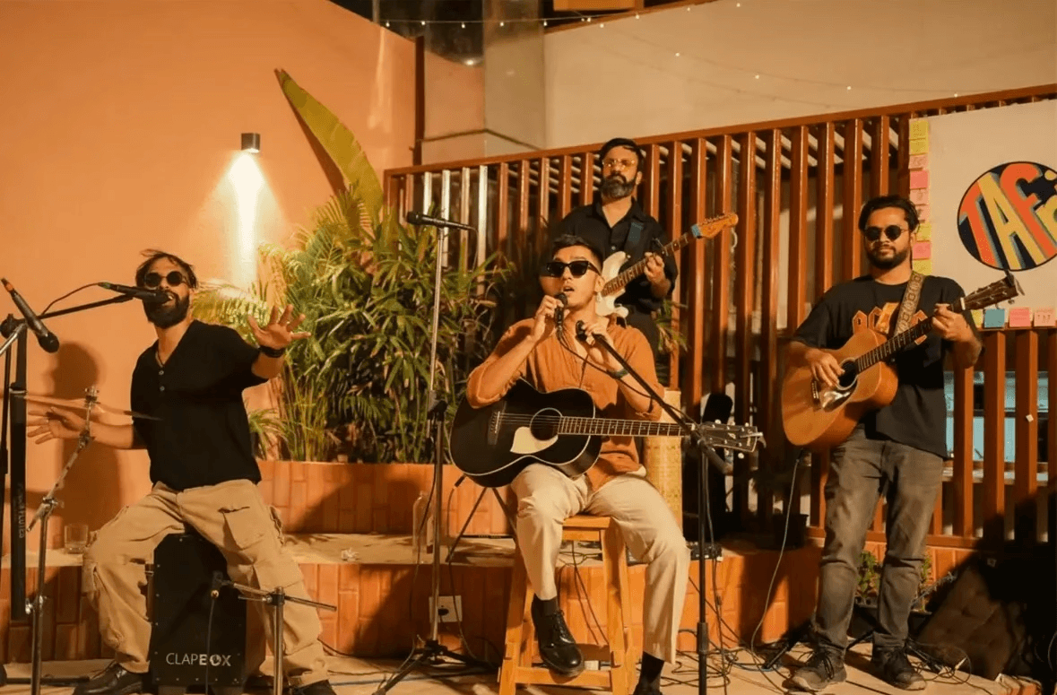 Band performing live music, four men playing guitars and singing.