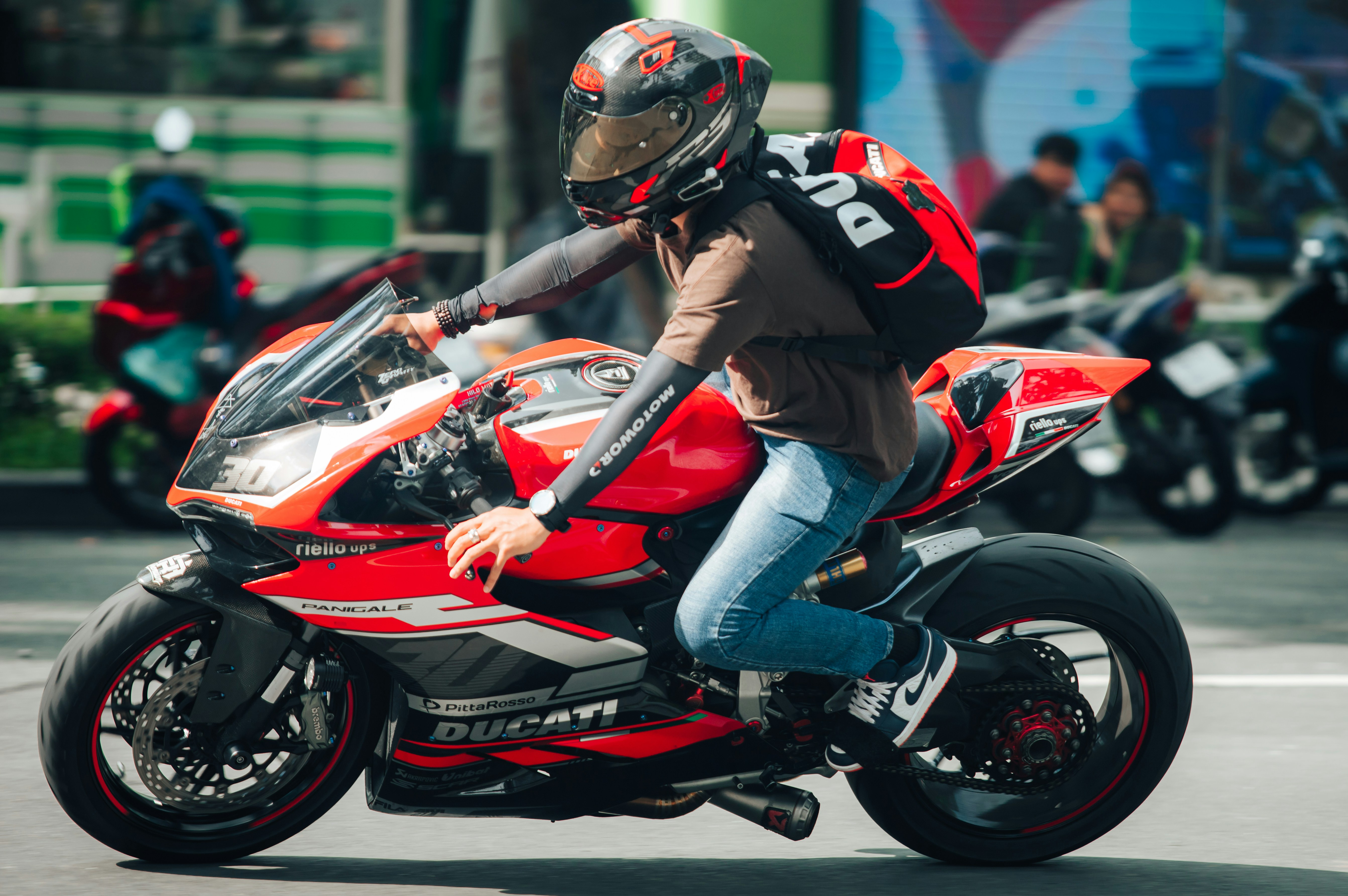 a man riding on the back of a red motorcycle