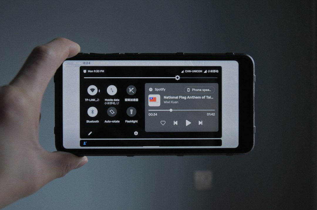 close-up of a ruggedized smartphone displaying a red alert icon and a fire safety checklist, next to a bright red fire extinguisher in a dimly lit hallway