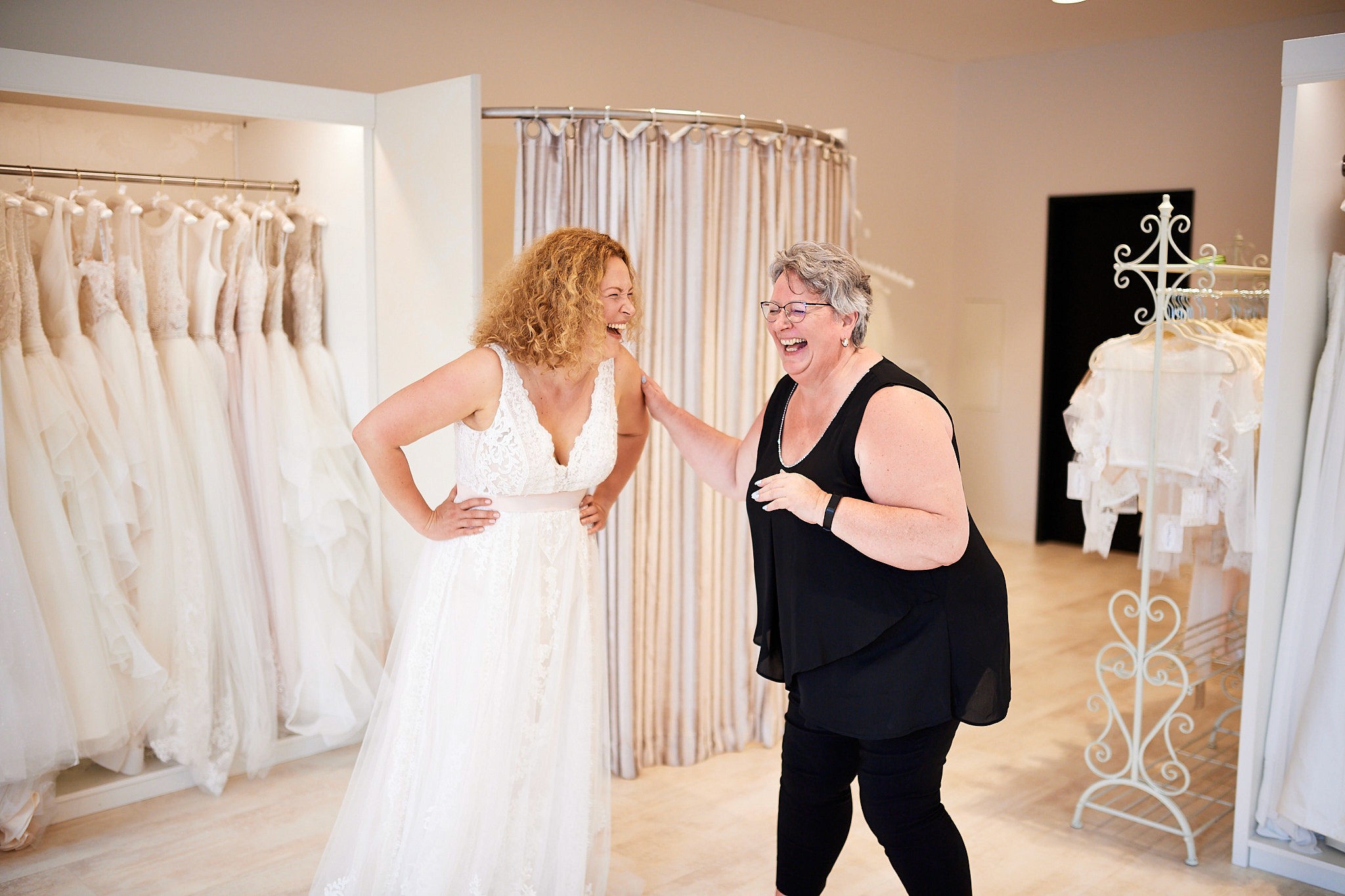 Herzlicher Moment bei Wedding Lounge Ingelheim - Braut im Traumkleid und Inhaberin Marion teilen ein glückliches Lachen während der Anprobe