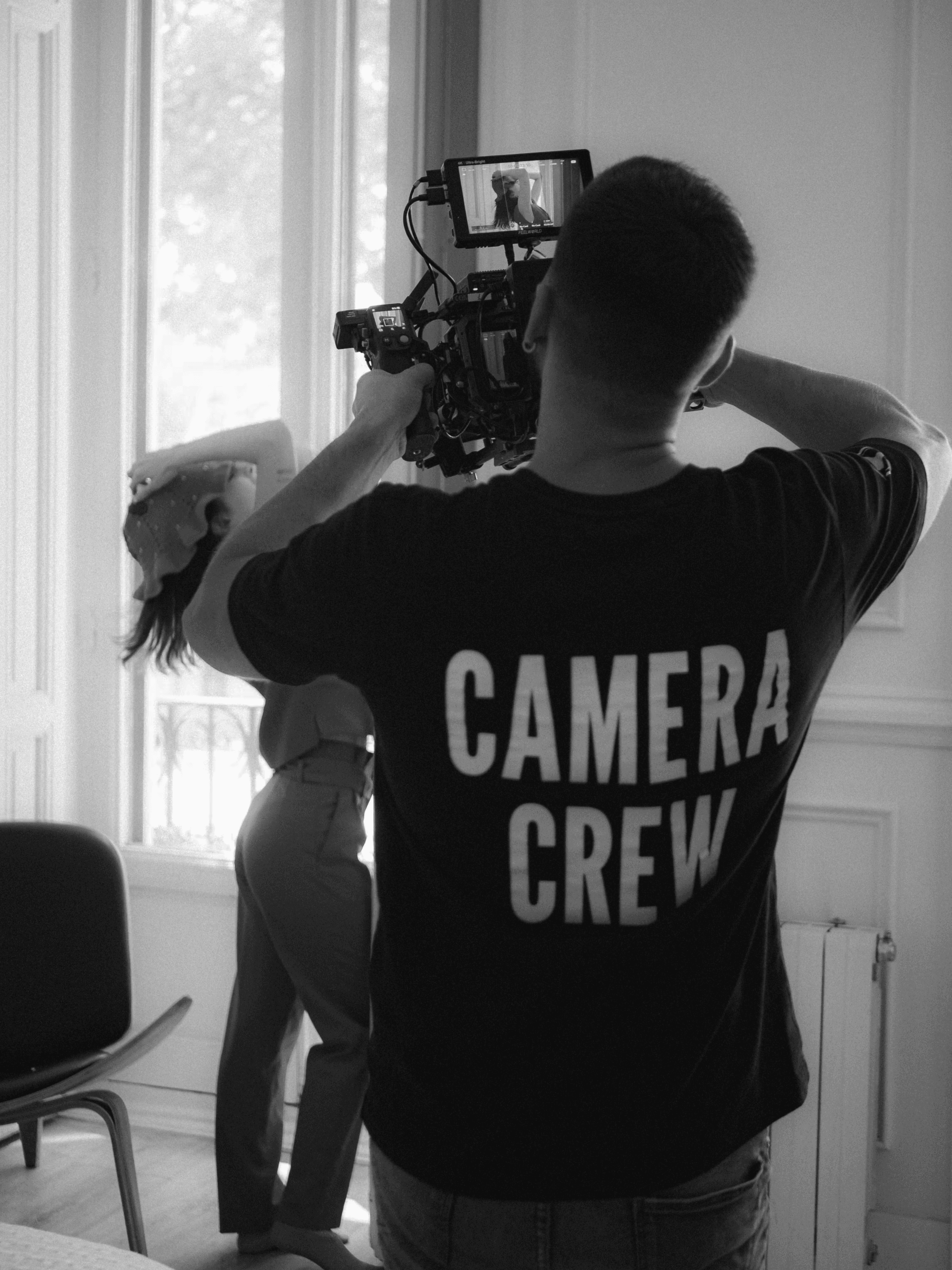 Camera crew filming a woman in red attire