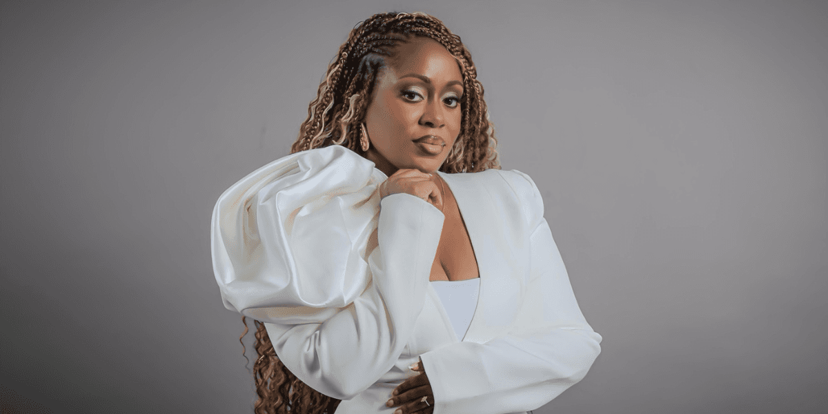 A woman with dreadlocks in a white jacket, representing the journey of self-discovery and shedding survival identities.