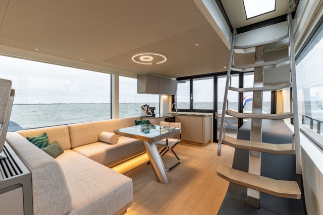 Luxury motor yacht main saloon interior showing EcoDeck composite flooring used throughout the living and galley space, demonstrating how EcoDeck's light oak finish transitions seamlessly from exterior decks to interior cabin floors for a cohesive, high-end look
