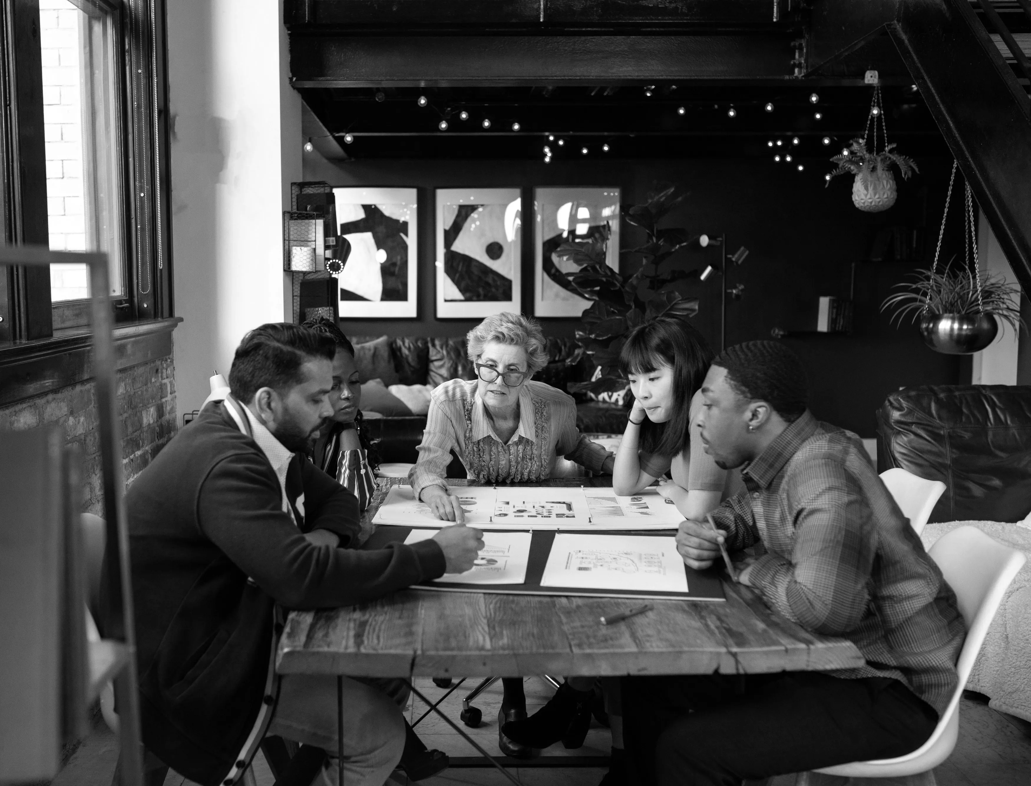 A black and white image of a group of people planning around a table.
