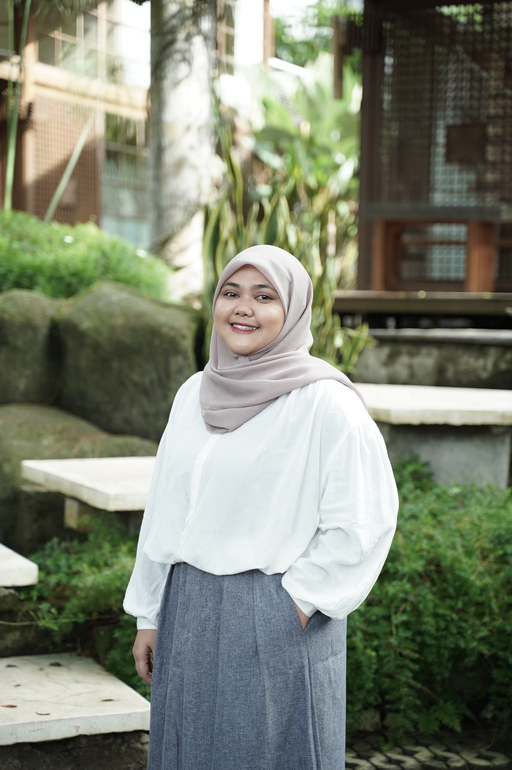A winding road cuts through rocky terrain, surrounded by patches of green grass and illuminated by sunlight.