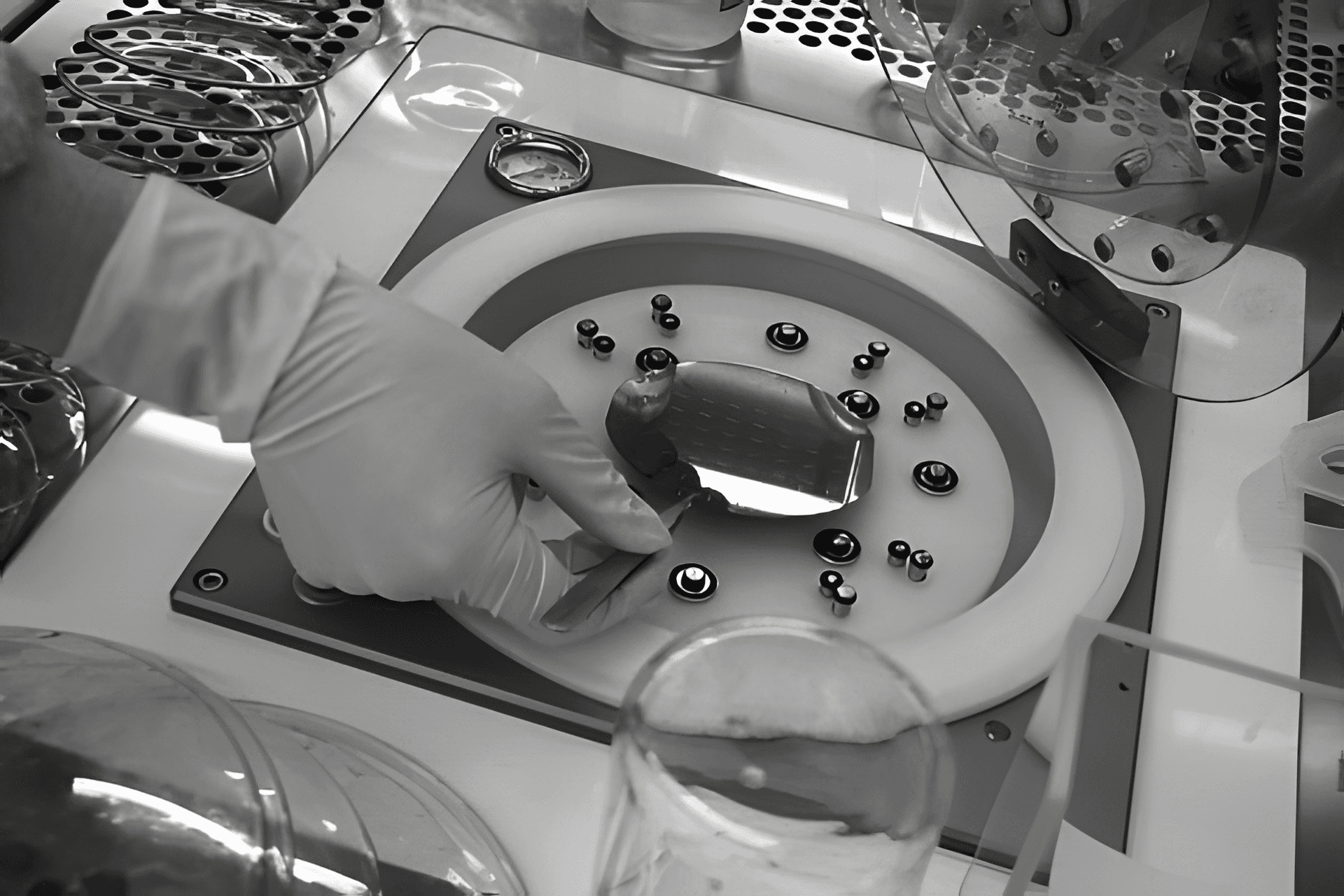 Gloved hand placing a microfabricated wafer onto a precision fixture inside a cleanroom laboratory.