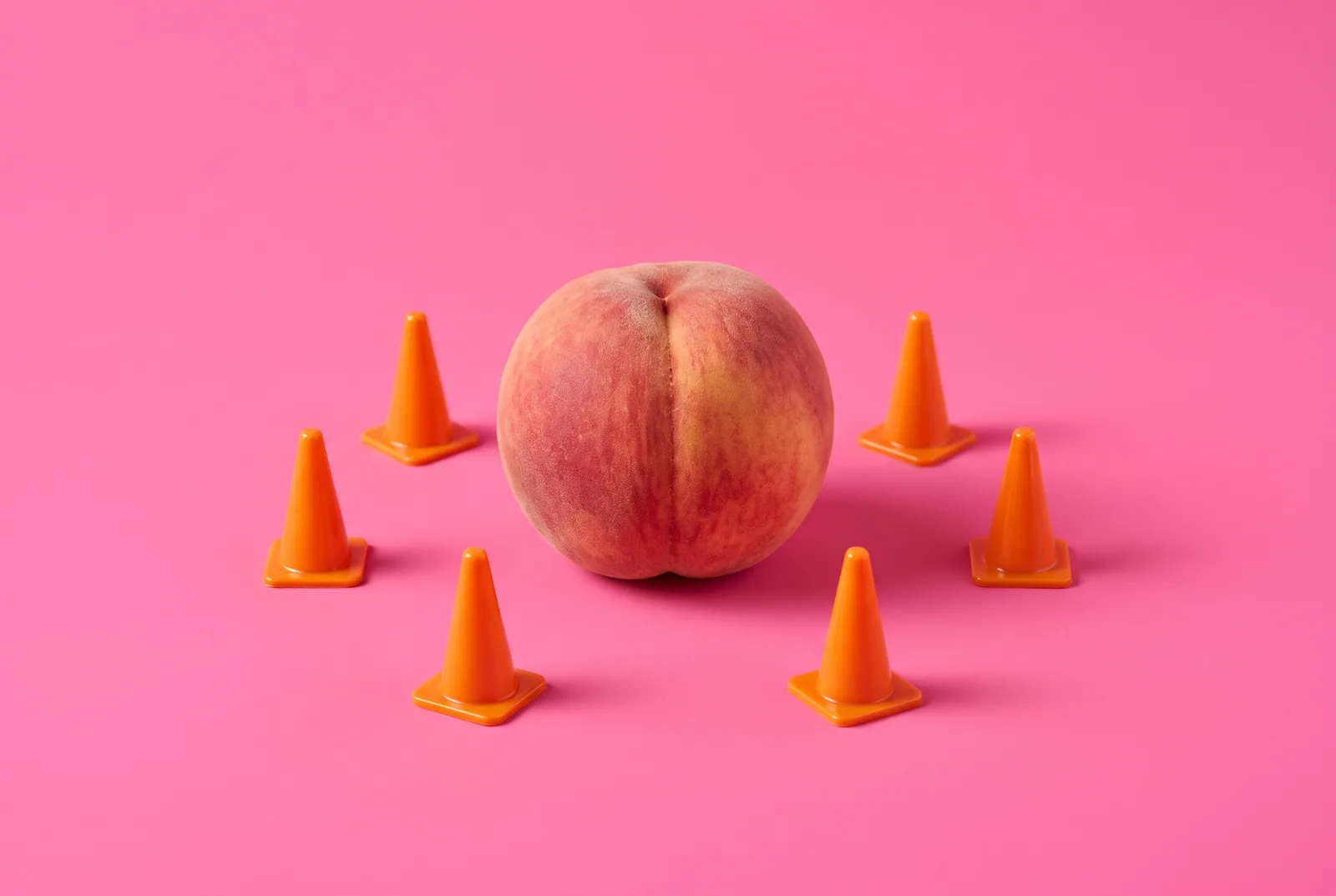 High-risk situations in a relapse prevention plan: a peach seen from behind surrounded by miniature orange traffic cones on a hot pink backdrop